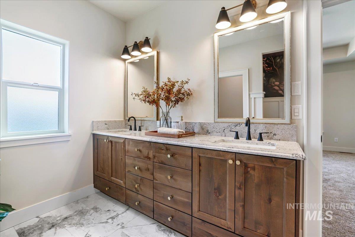 Full bath featuring double vanity and marble look tile flooring