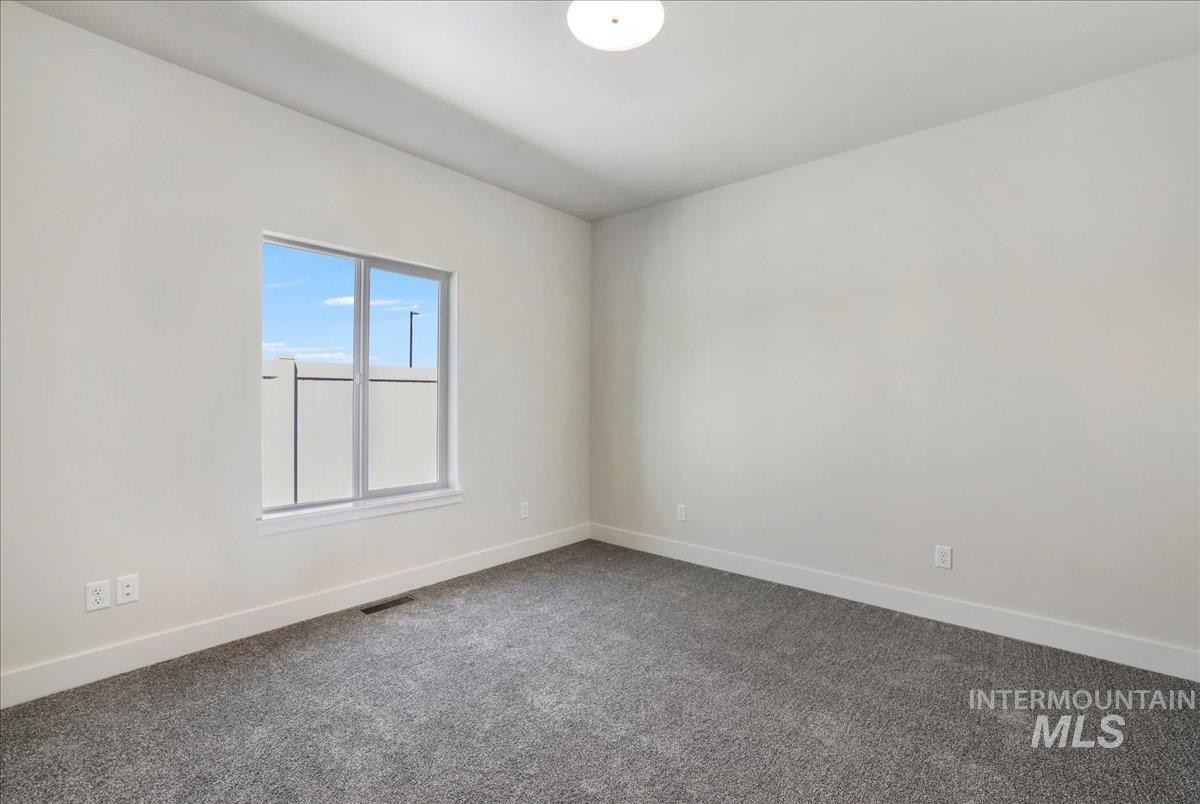 Empty room with baseboards and dark colored carpet