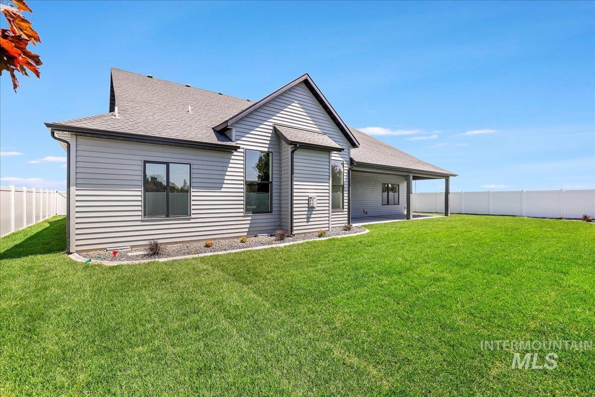 Rear view of house with a shingled roof and a fenced backyard