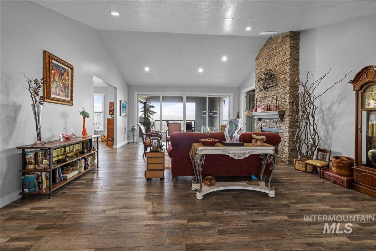 Living room featuring lofted ceiling, wood finished floors, a fireplace, and recessed lighting