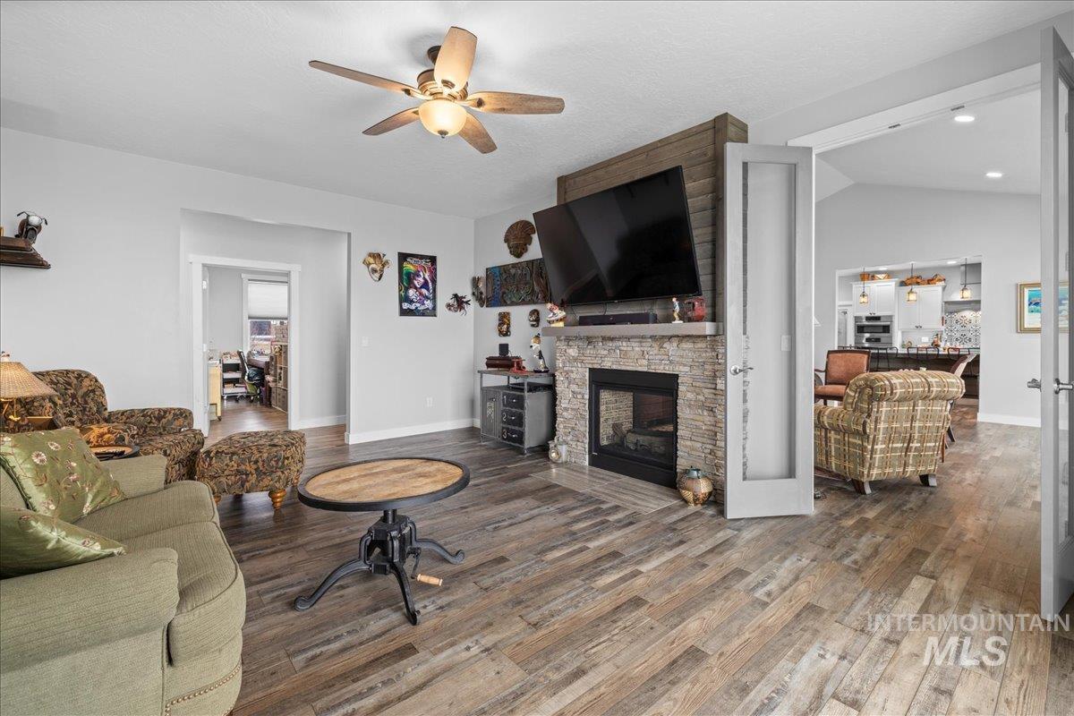 Living area featuring a ceiling fan, wood finished floors, a fireplace, and lofted ceiling