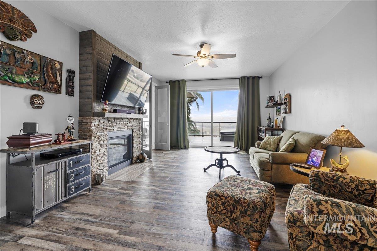 Living room featuring ceiling fan, wood finished floors, a fireplace, and a textured ceiling