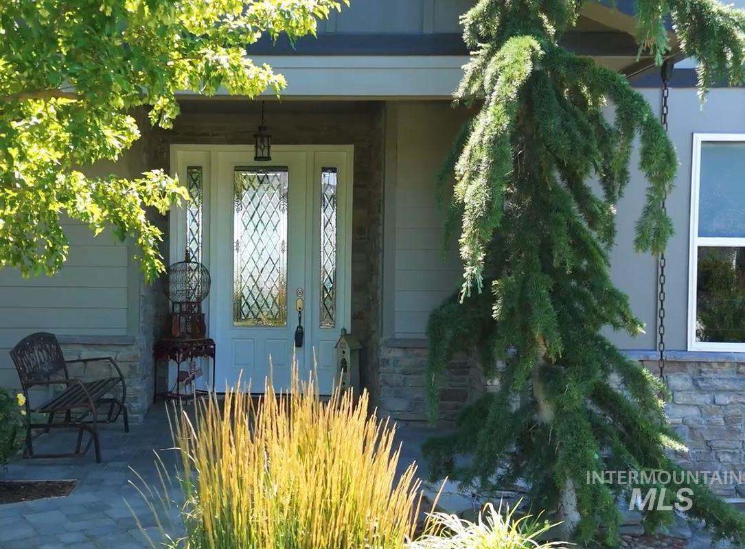 View of exterior entry featuring stone siding and a porch