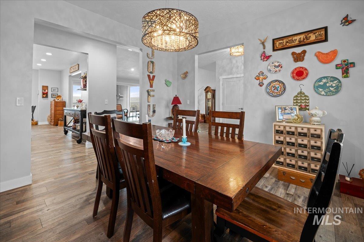 Dining room with a chandelier, wood finished floors, and recessed lighting