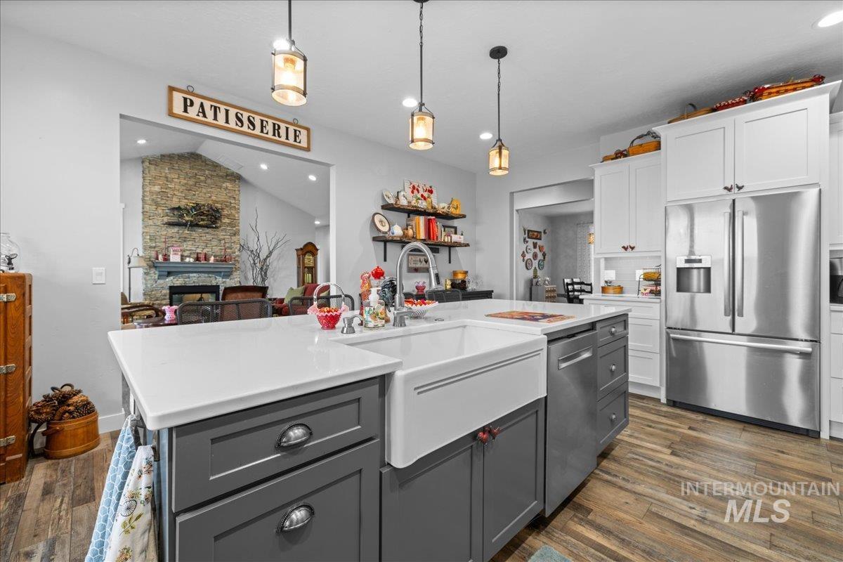 Kitchen with appliances with stainless steel finishes, white cabinets, dark wood-style flooring, gray cabinets, and light countertops
