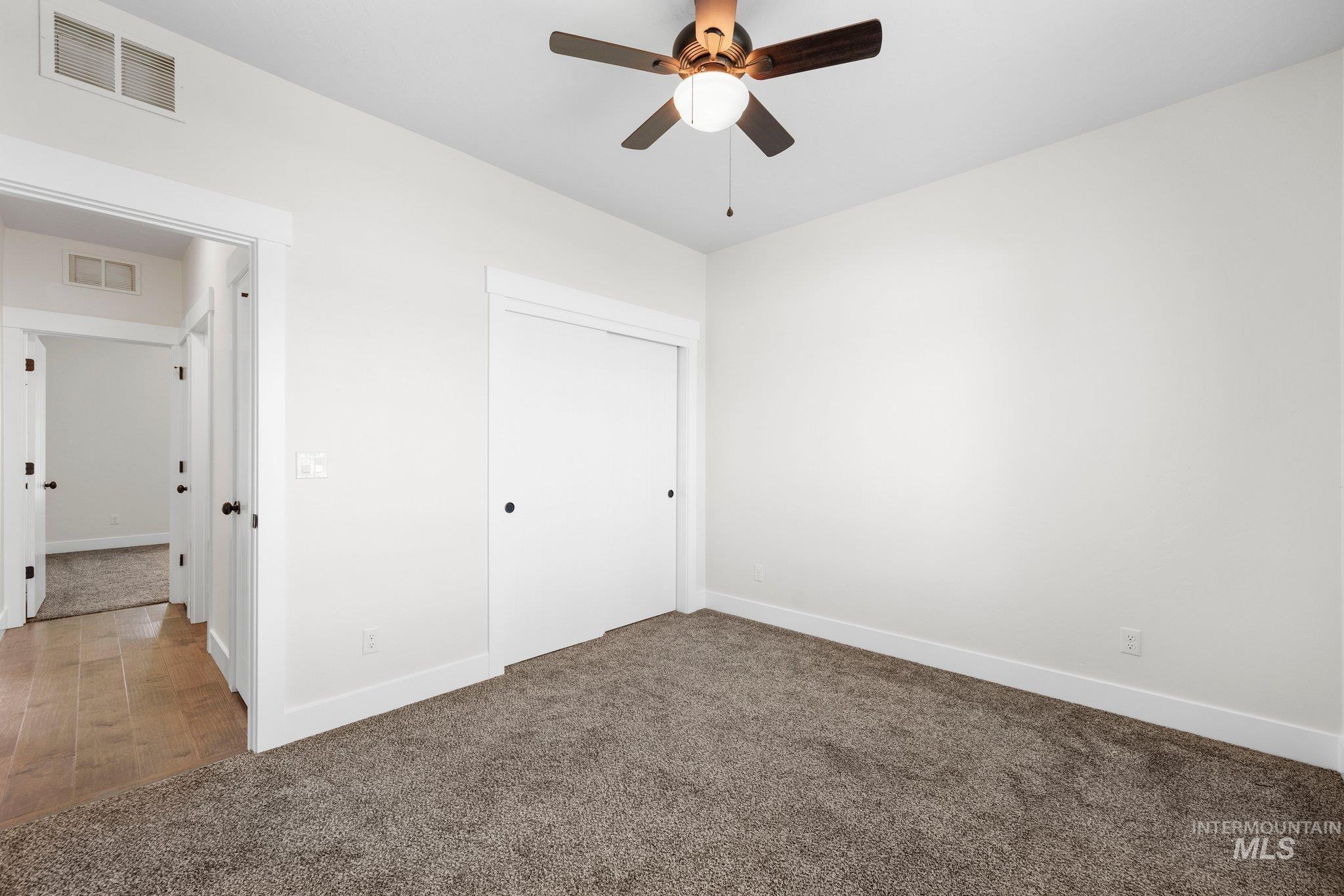 Unfurnished bedroom with carpet, a closet, and a ceiling fan