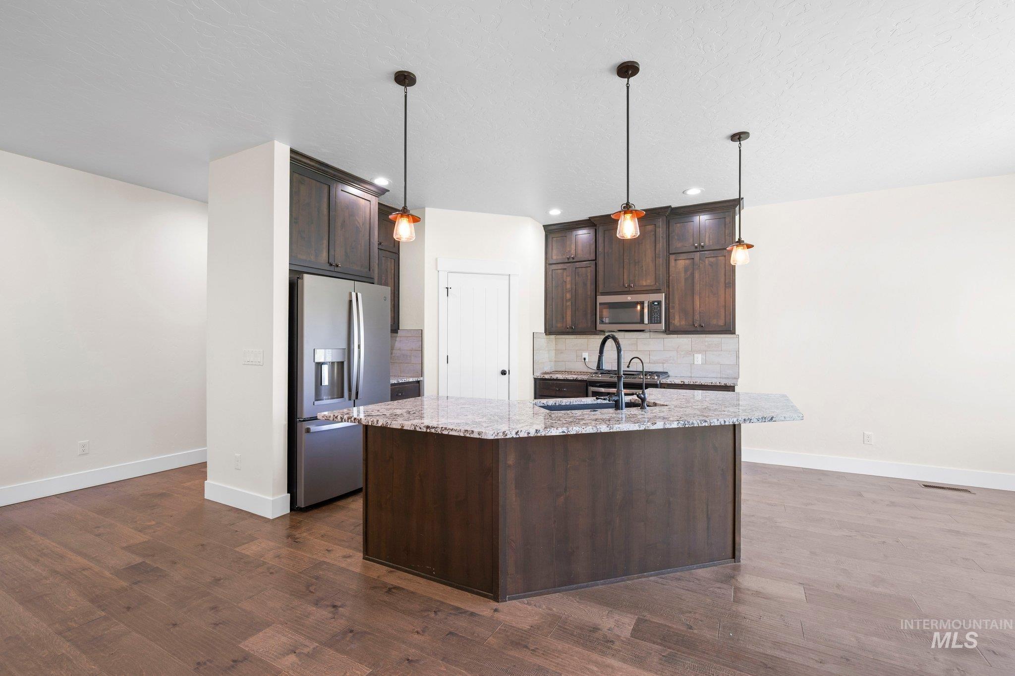 Kitchen with stainless steel appliances, dark brown cabinetry, tasteful backsplash, dark wood-style flooring, and recessed lighting