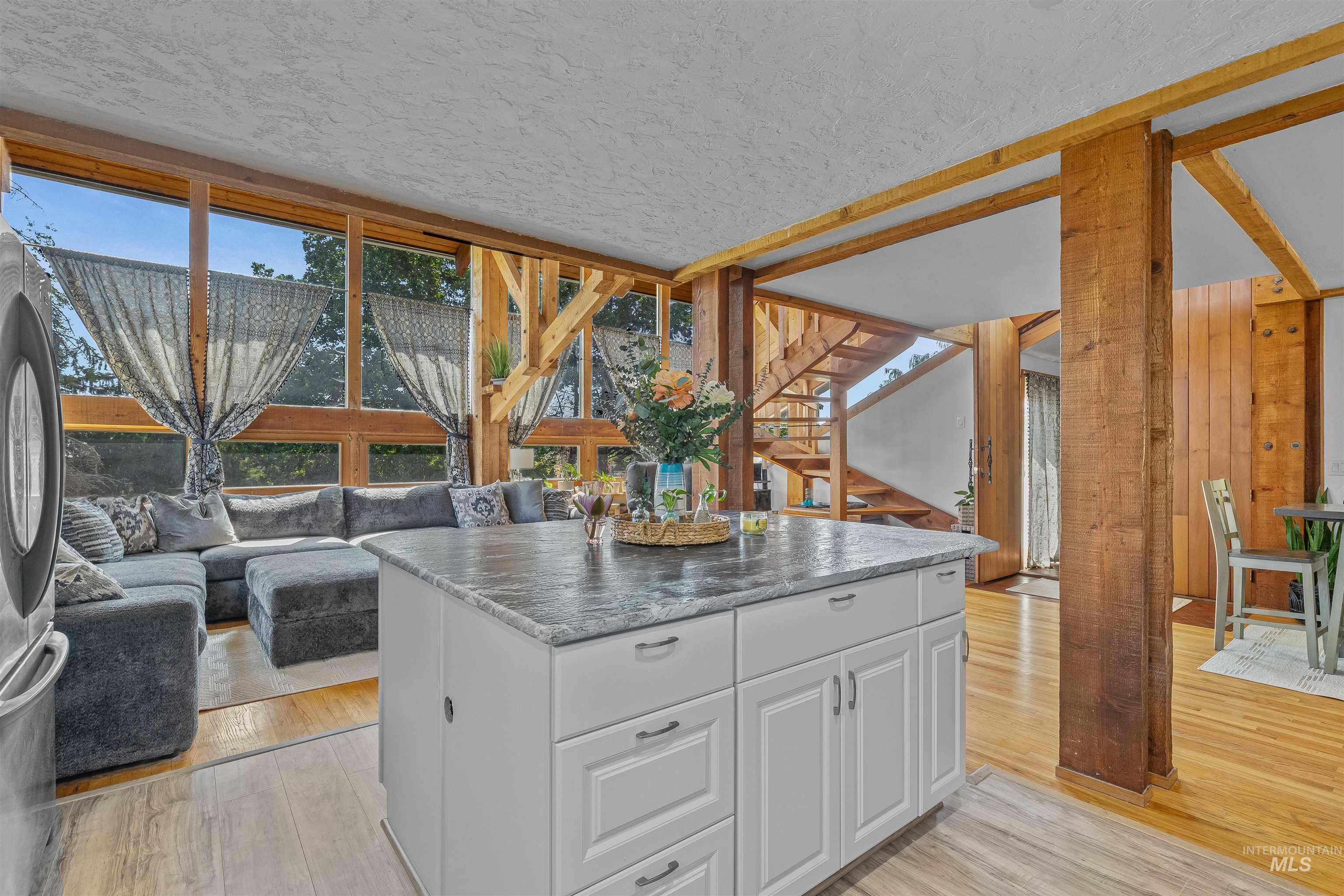 Kitchen featuring light wood-style floors, white cabinets, a textured ceiling, a kitchen island, and open floor plan