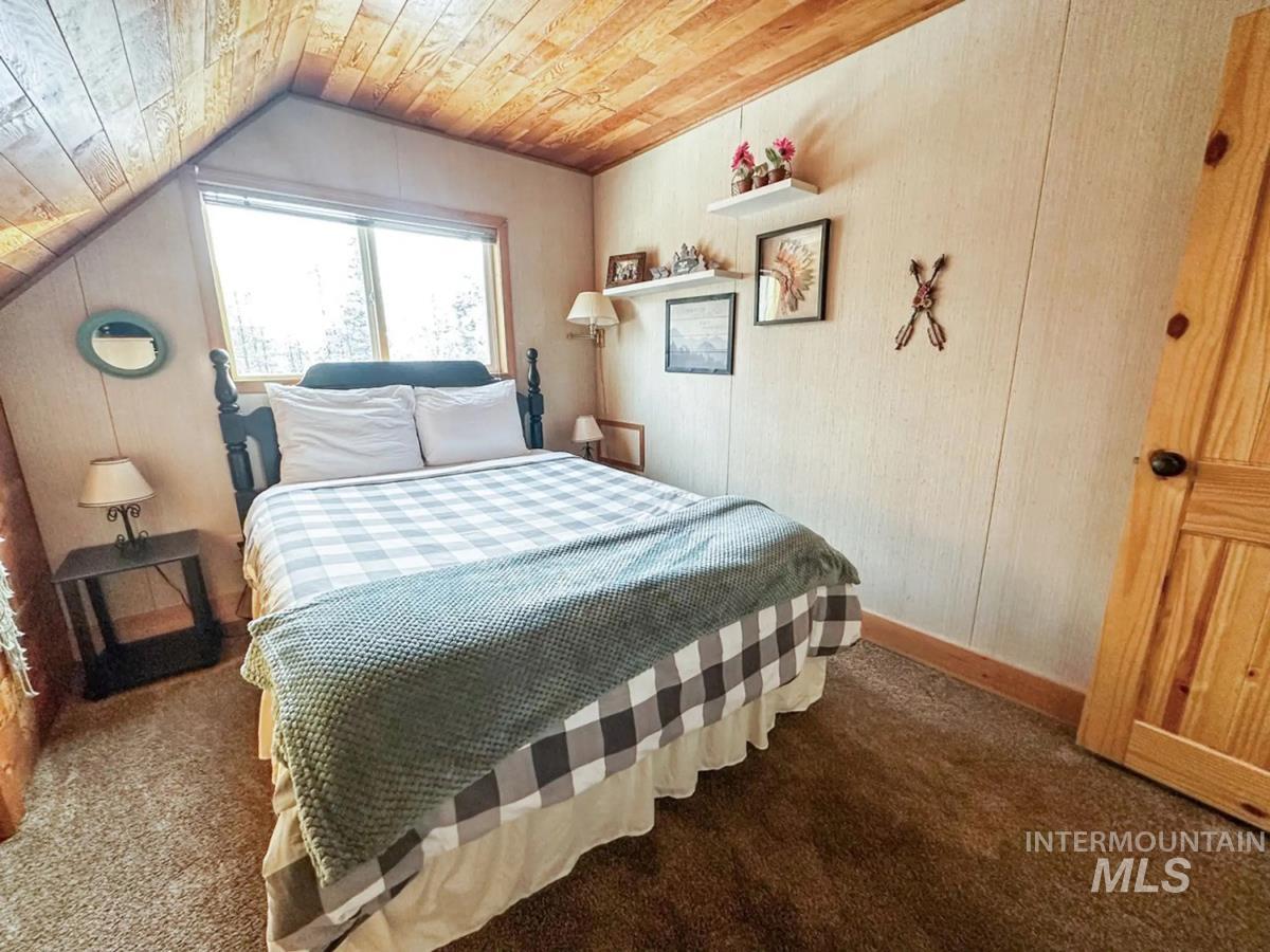 Bedroom with wood ceiling, carpet floors, and vaulted ceiling