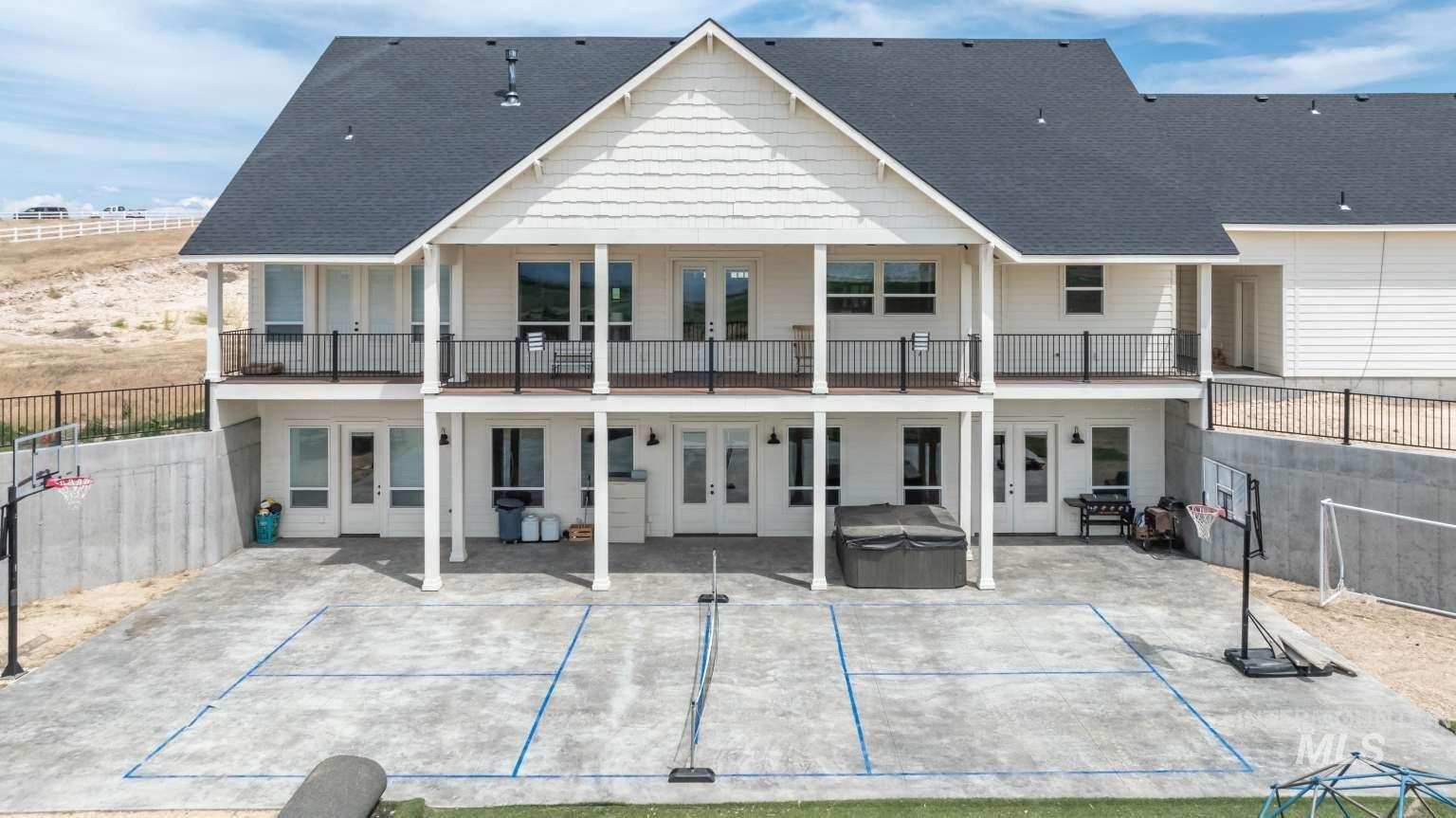 Back of property featuring french doors, a hot tub, a patio area, a balcony, and roof with shingles