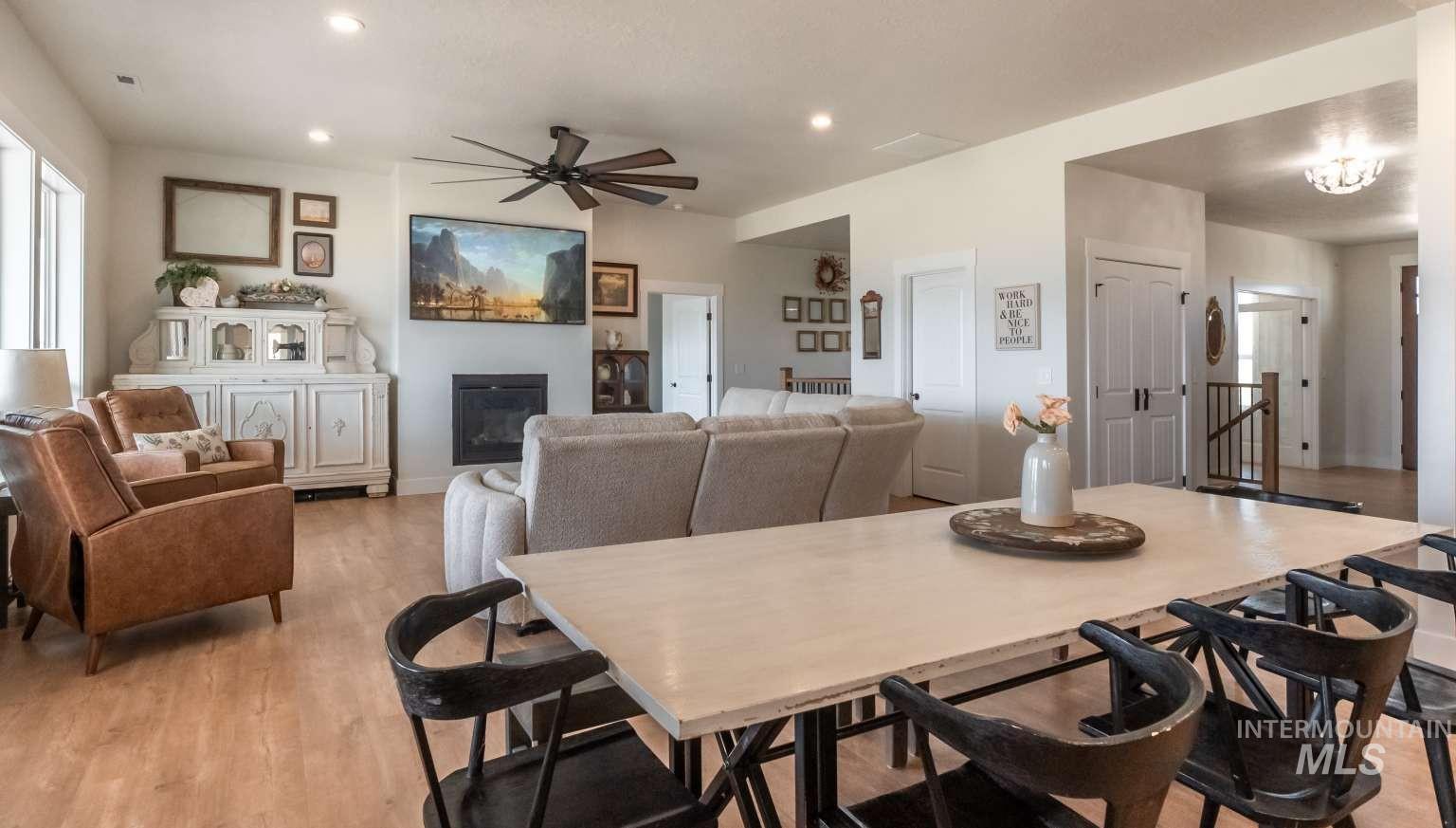 Dining space with ceiling fan, light wood-style flooring, recessed lighting, and a glass covered fireplace