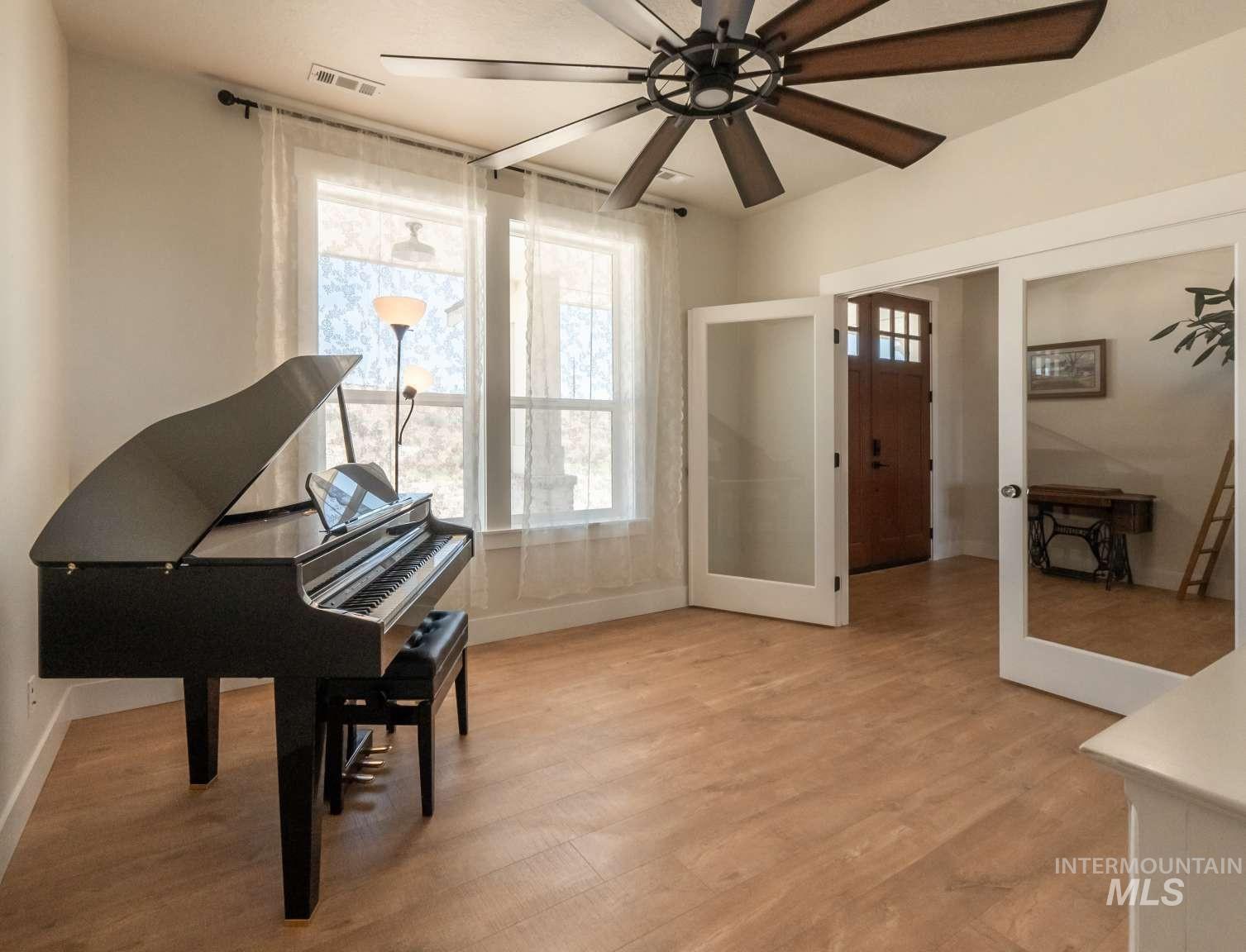 Sitting room with plenty of natural light, french doors, ceiling fan, and light wood-type flooring