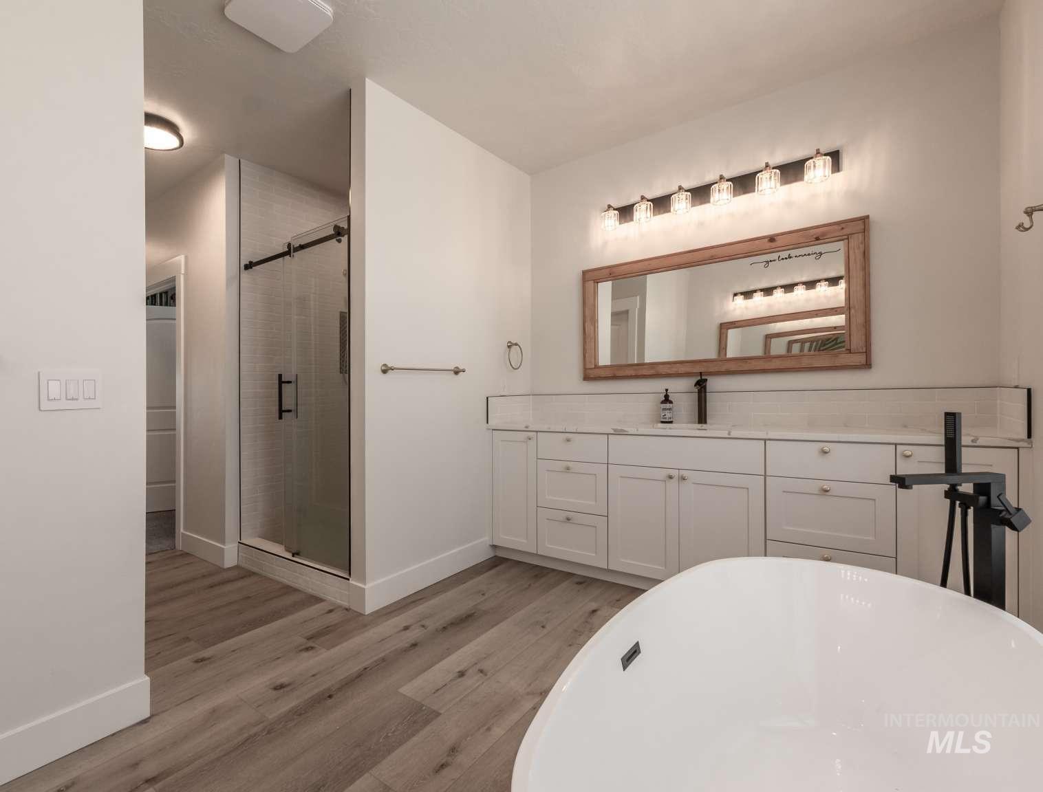Bathroom featuring a soaking tub, a shower stall, wood finished floors, and vanity