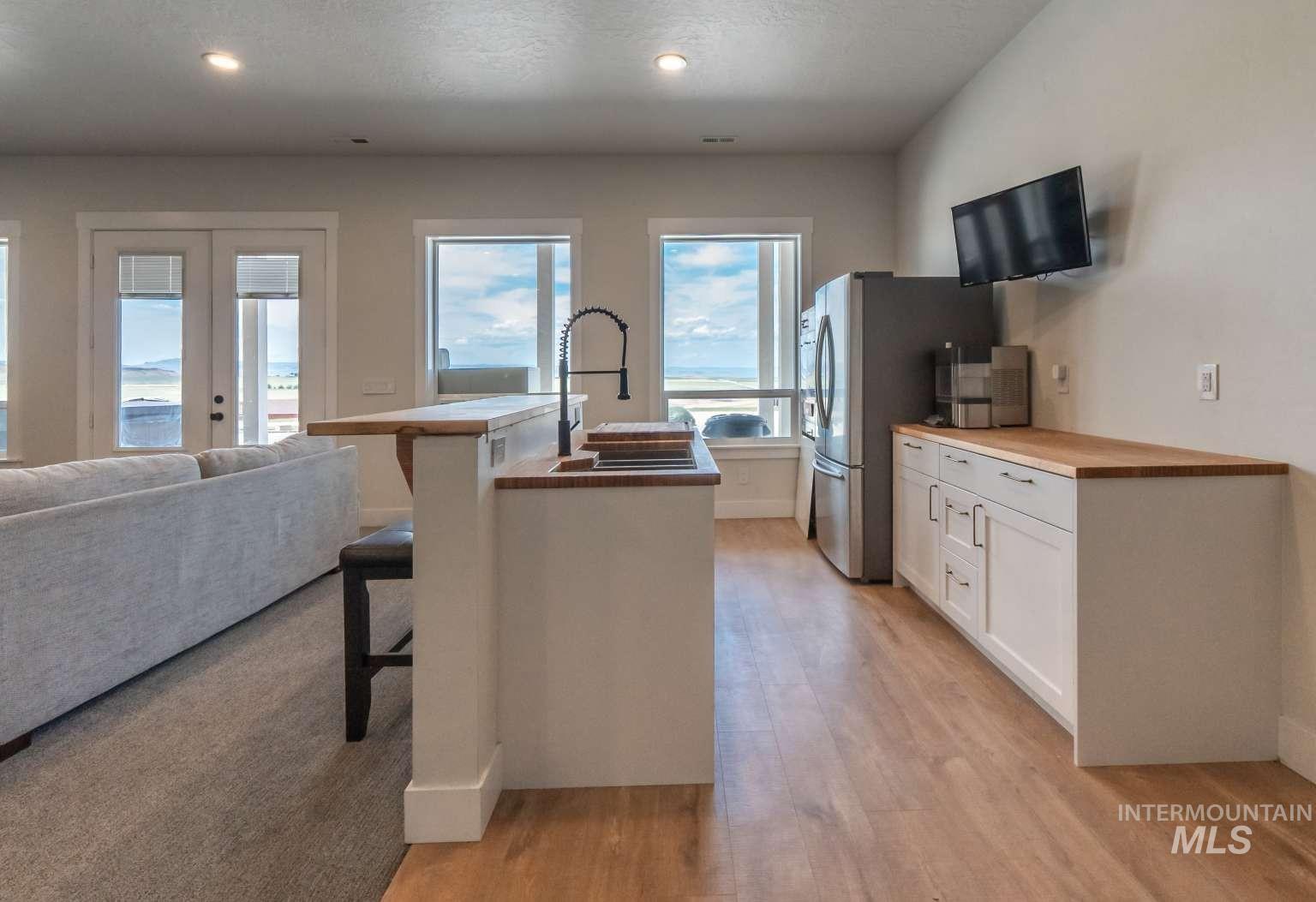Kitchen featuring light wood-type flooring, white cabinets, a kitchen bar, a kitchen island with sink, and open floor plan