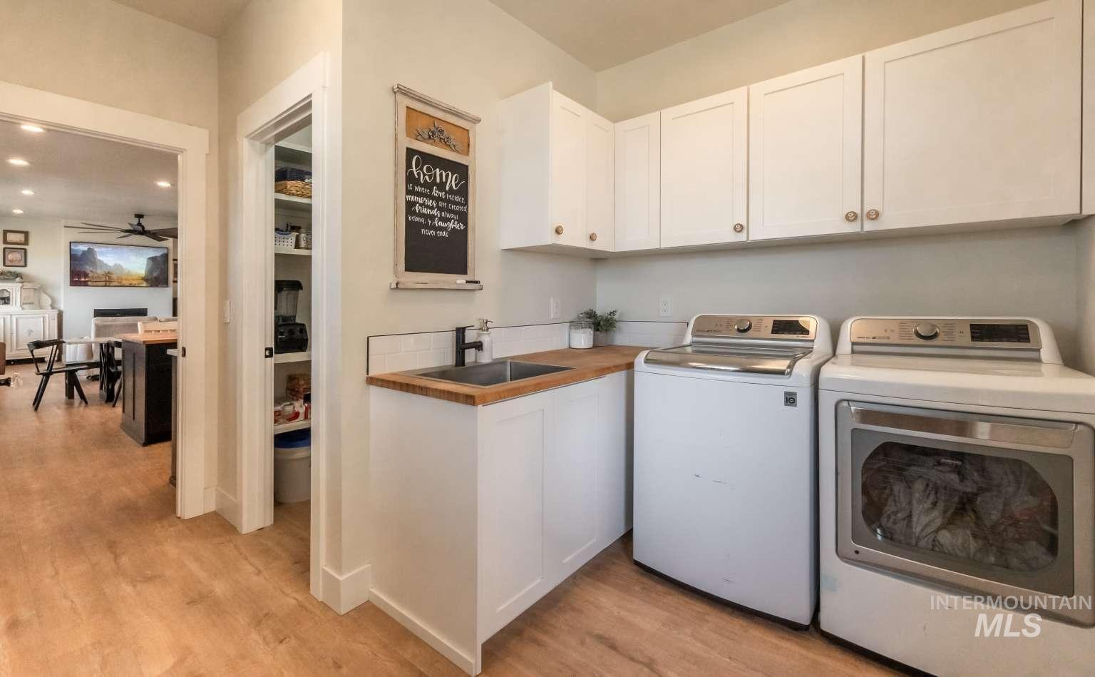Washroom featuring cabinet space, washing machine and dryer, light wood-style flooring, ceiling fan, and recessed lighting