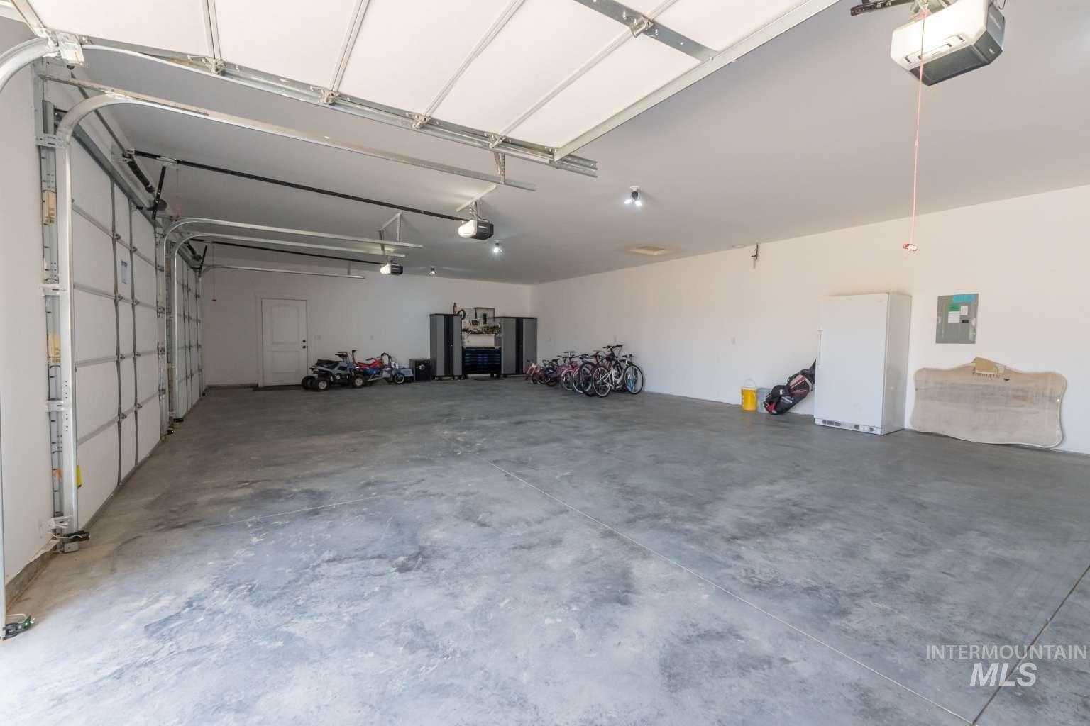 Garage featuring a garage door opener, electric panel, and freestanding refrigerator