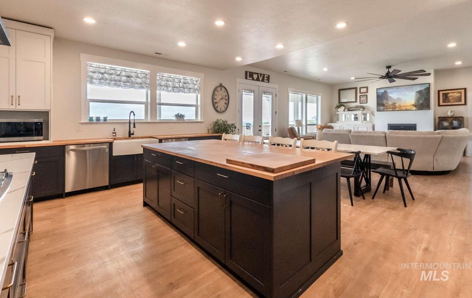 Kitchen featuring stainless steel appliances, butcher block counters, white cabinetry, recessed lighting, and dark cabinets