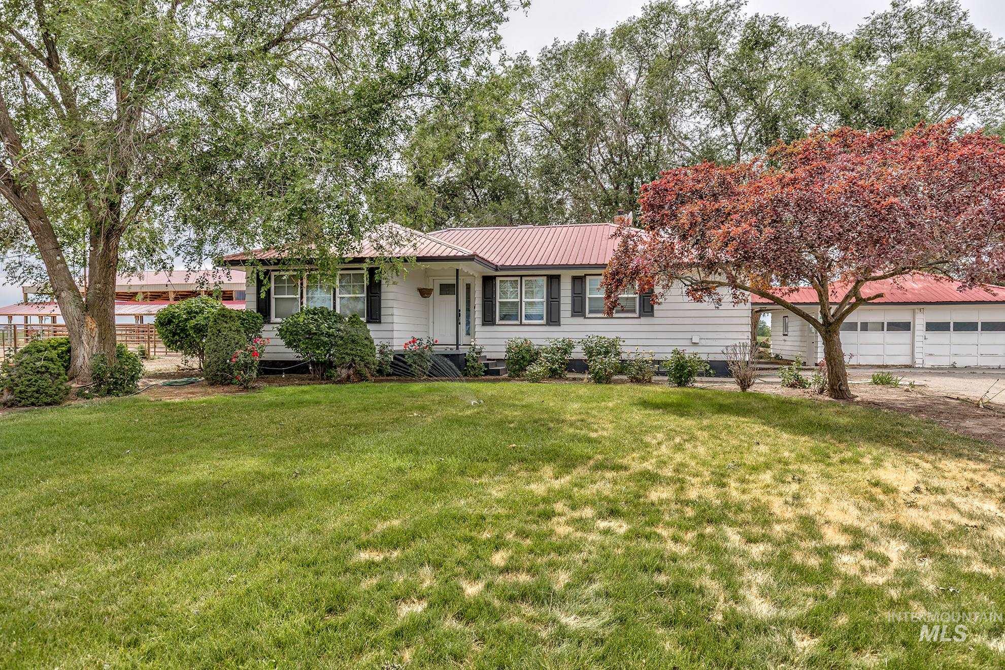 Ranch-style home with a garage, a front yard, and a metal roof