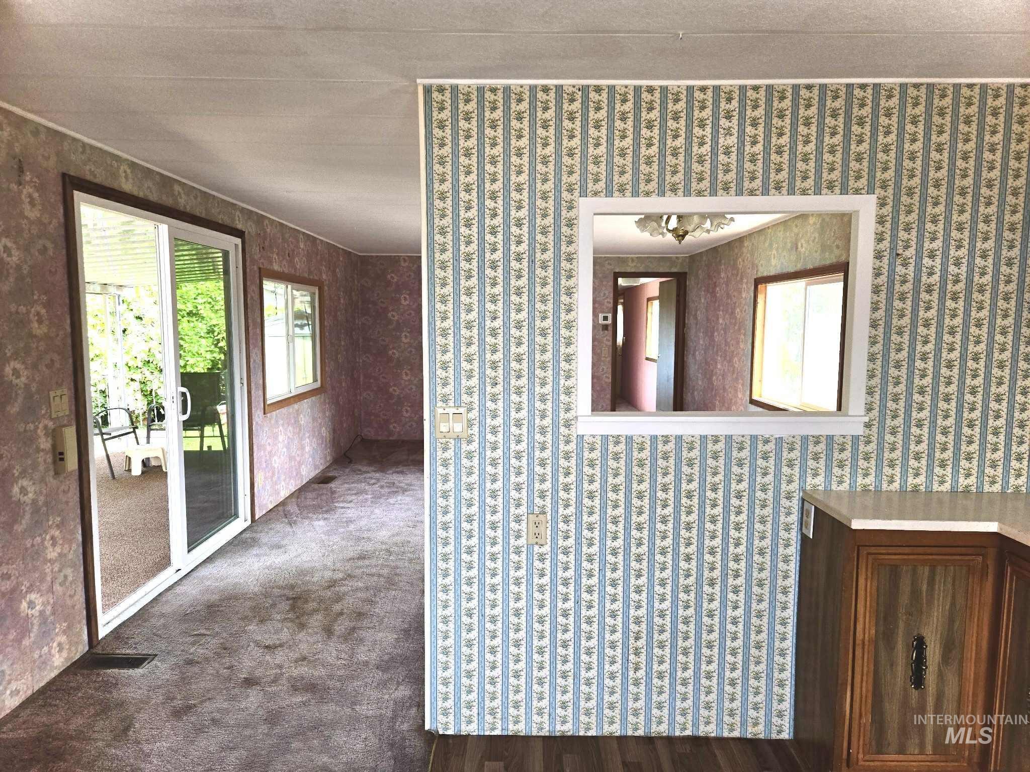 Carpeted spare room featuring wallpapered walls
