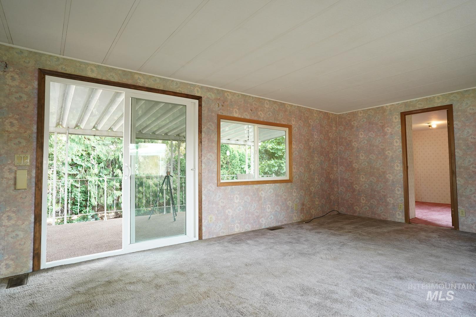 Carpeted empty room featuring wallpapered walls