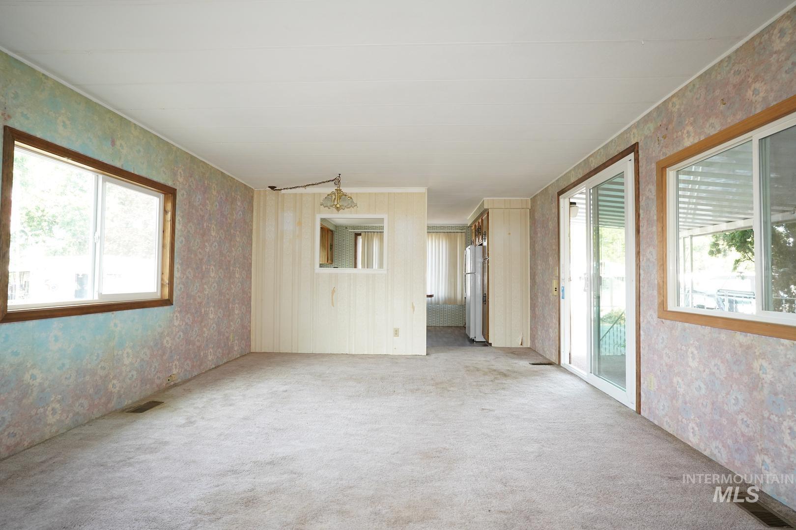 Spare room with wallpapered walls and light colored carpet