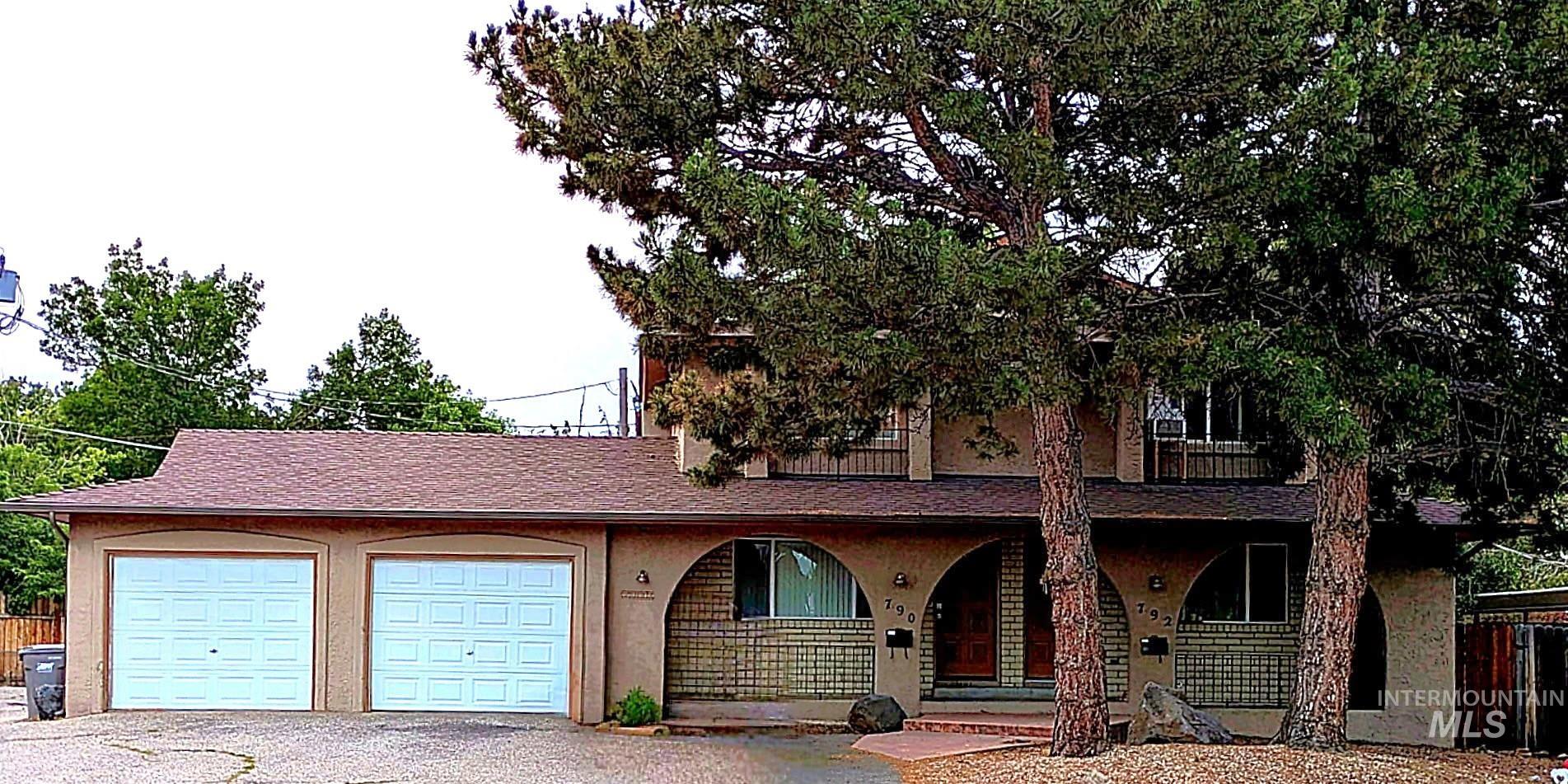 View of front facade featuring a porch, a garage, driveway, and stucco siding