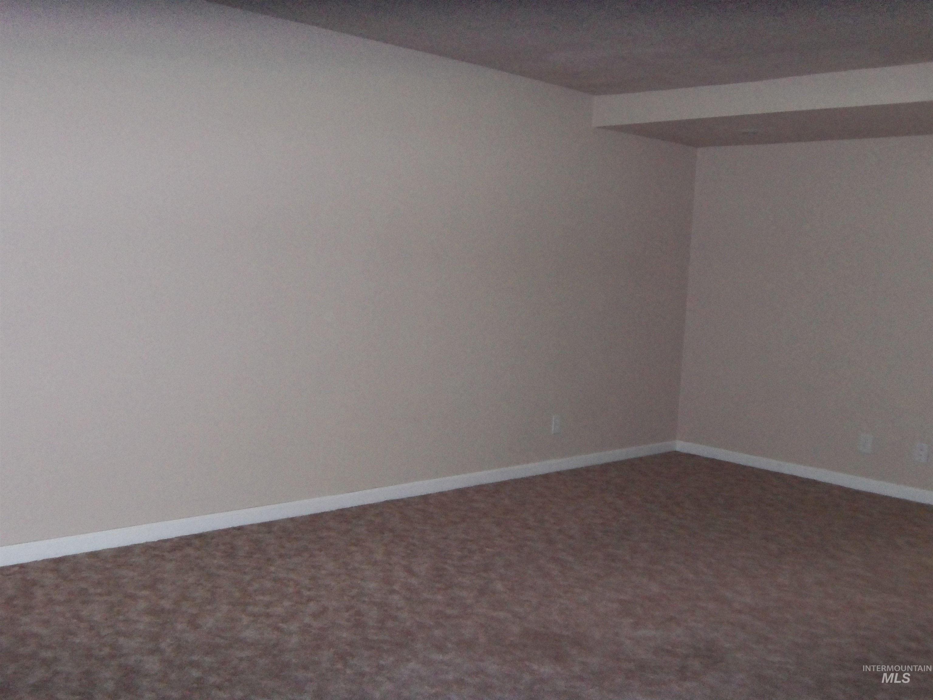 Spare room featuring carpet flooring and baseboards