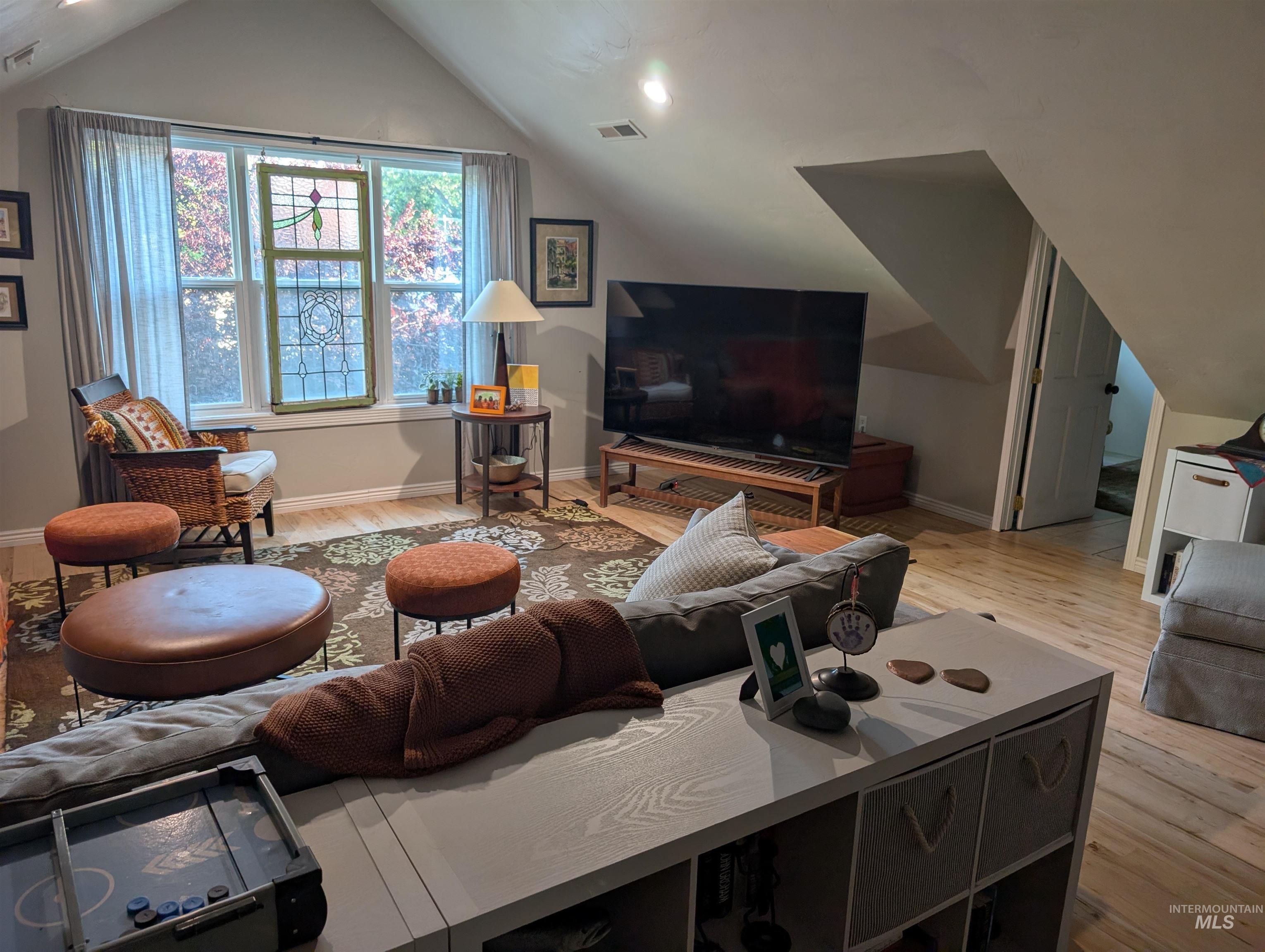 Living room featuring light wood-style flooring and vaulted ceiling