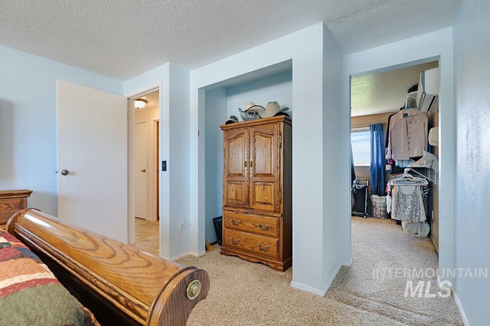 Bedroom featuring light colored carpet, a textured ceiling, and an AC wall unit