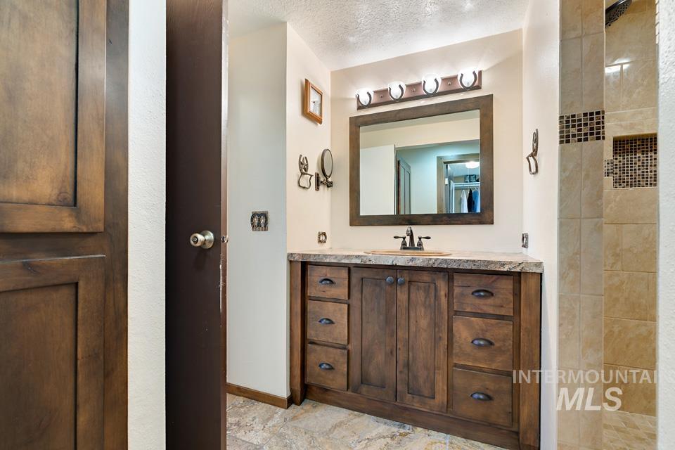 Bathroom with vanity, a tile shower, and a textured ceiling