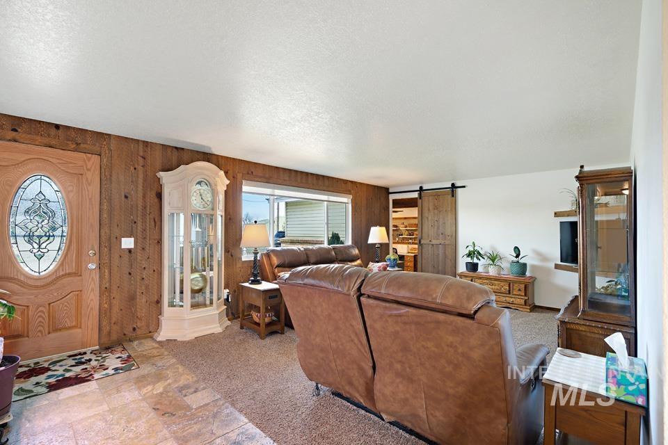 Living area featuring a barn door, wooden walls, and a textured ceiling