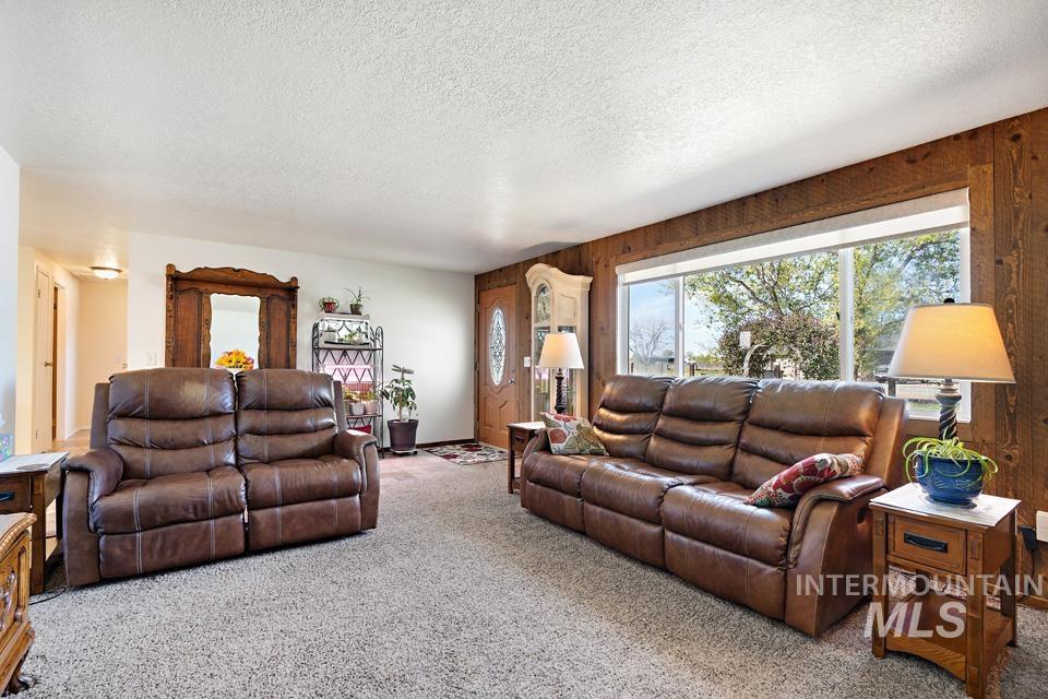 Carpeted living room with a textured ceiling and wood walls