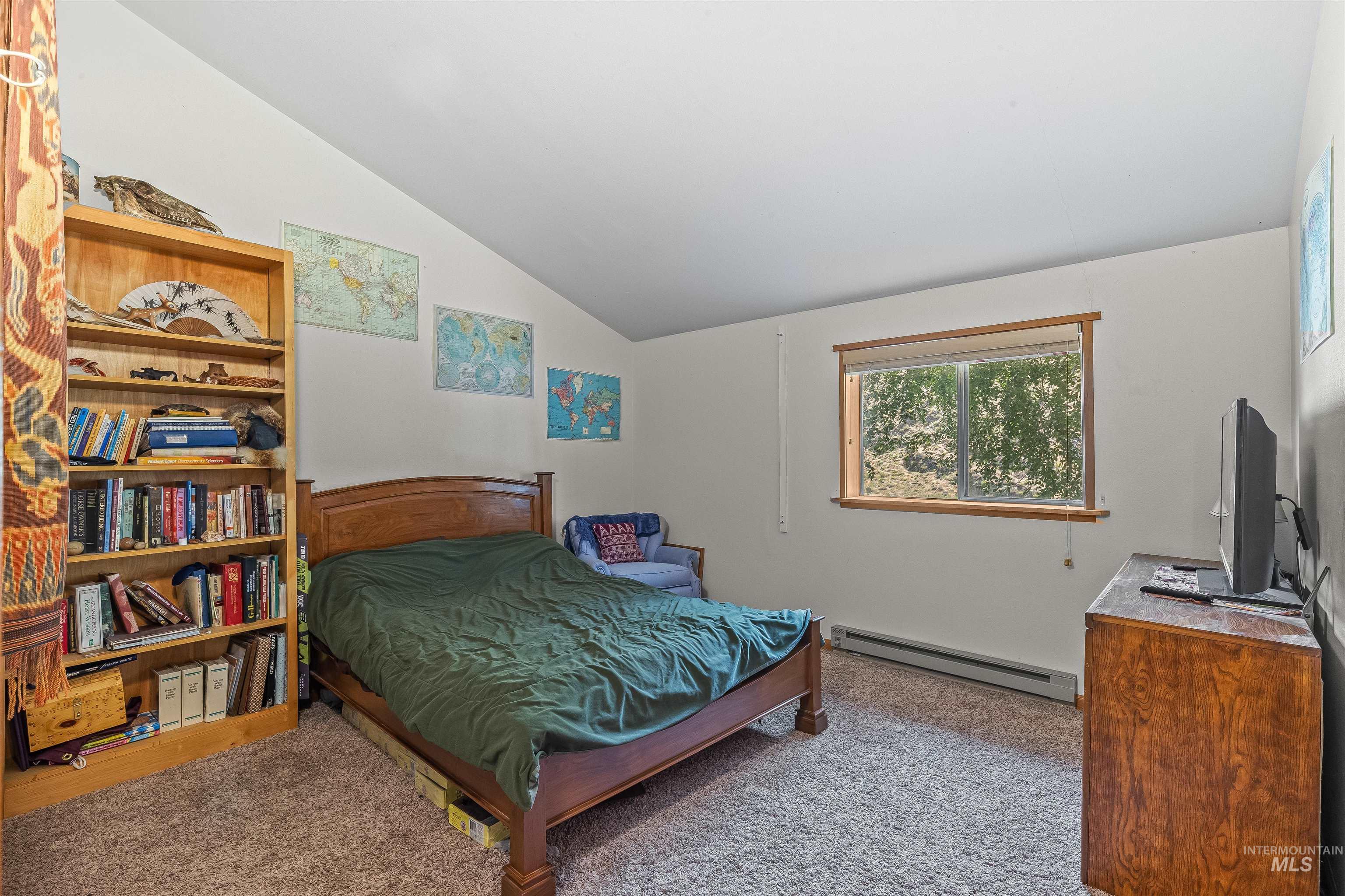 Carpeted bedroom featuring a baseboard radiator and lofted ceiling