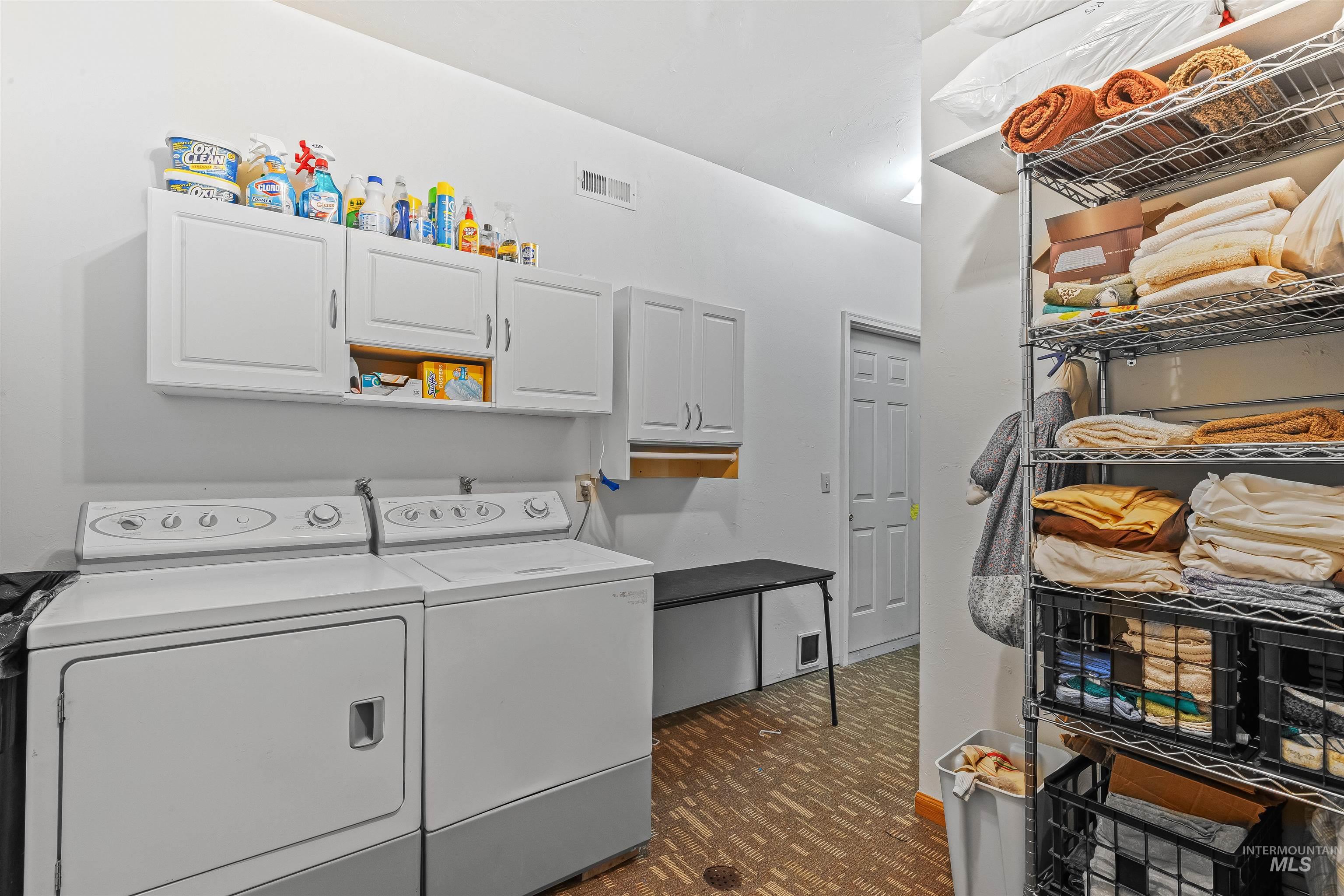 Laundry room featuring cabinet space, washing machine and dryer, and dark floors