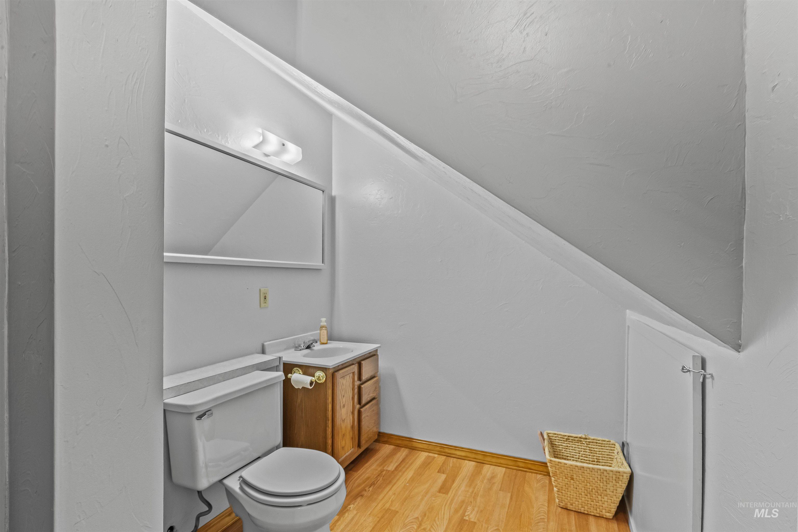 Half bath featuring wood finished floors and vanity