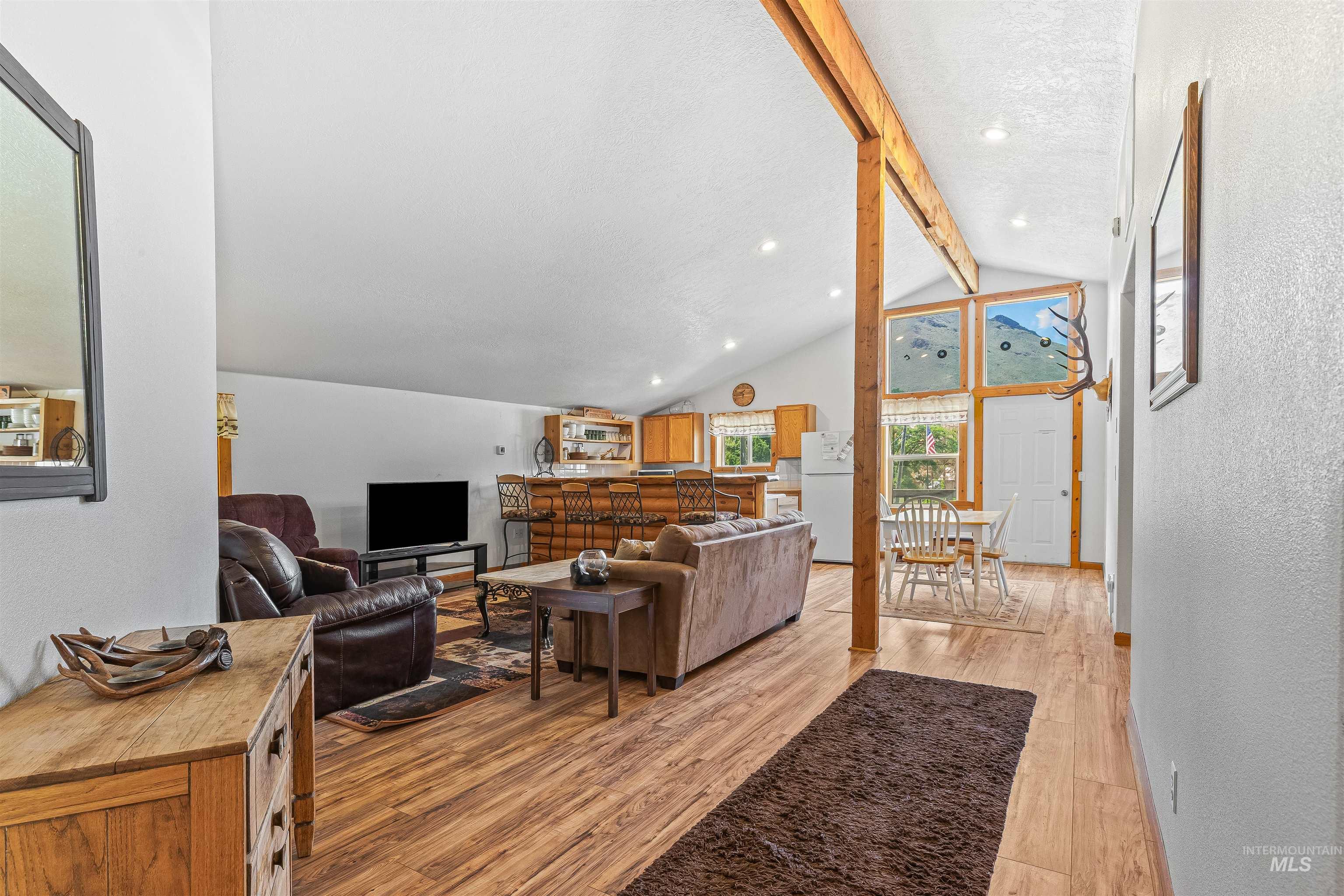 Living room with light wood finished floors, a textured wall, and recessed lighting