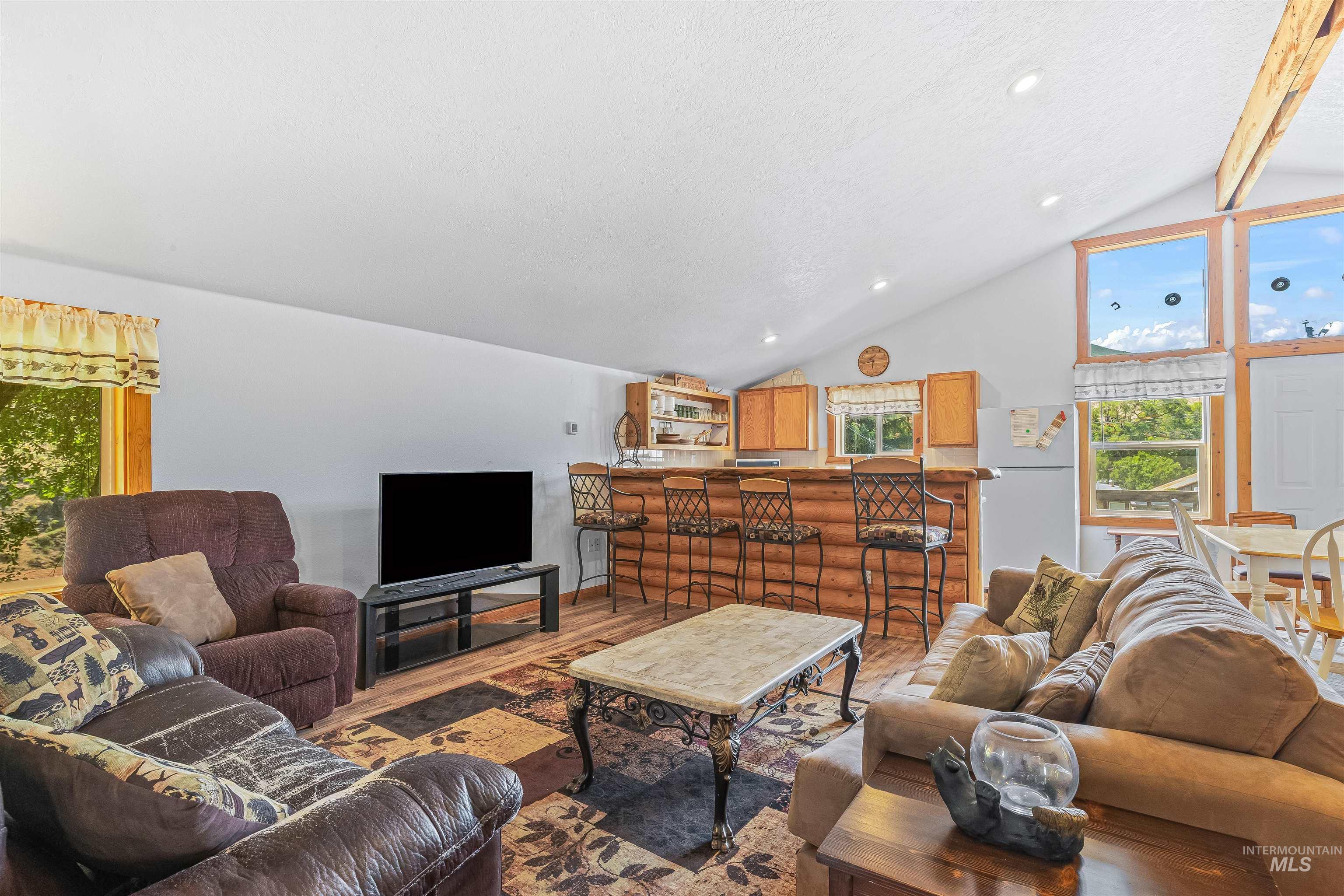 Living room with wood finished floors, healthy amount of natural light, a textured ceiling, and recessed lighting