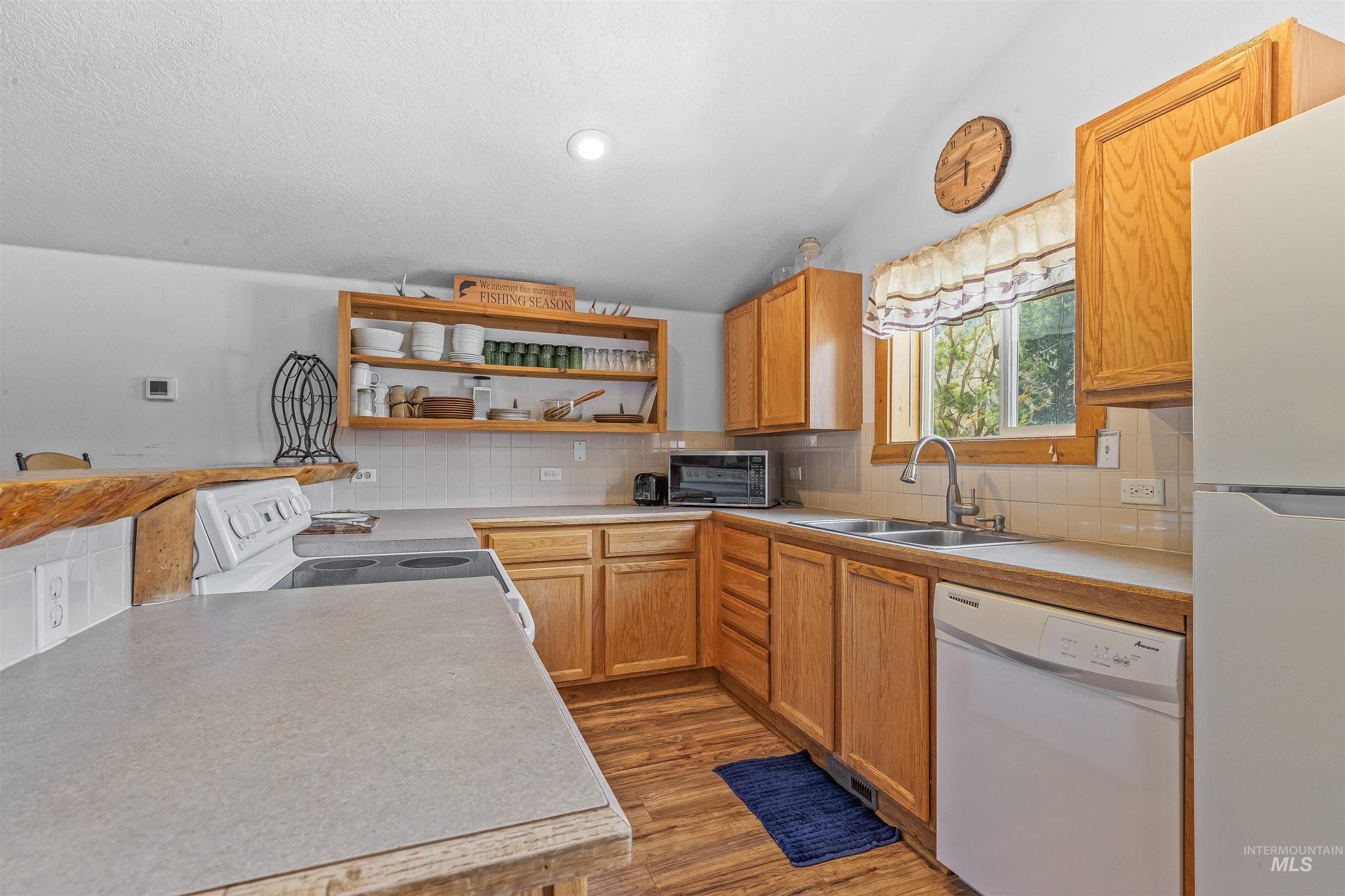 Kitchen with white appliances, open shelves, light wood-style flooring, decorative backsplash, and light countertops