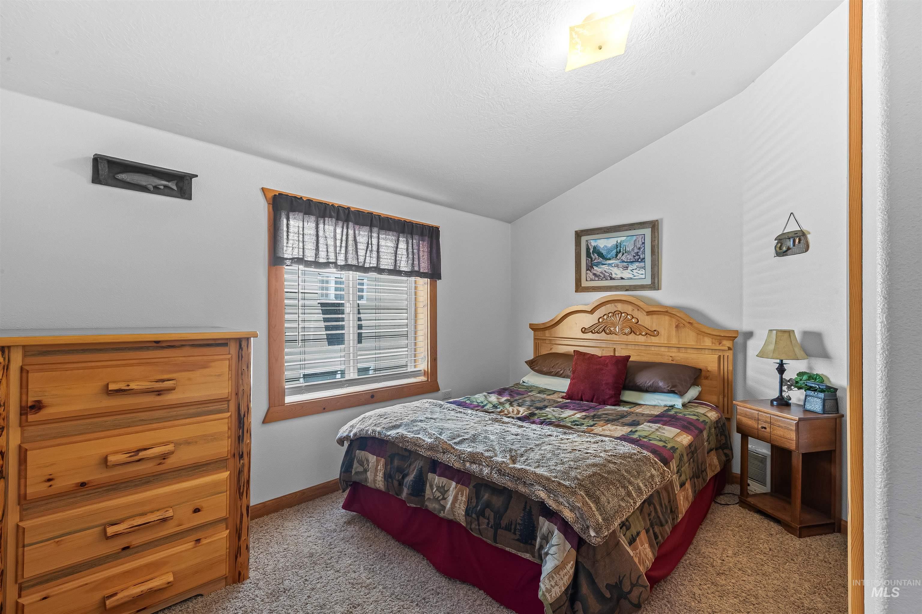 Bedroom featuring carpet flooring, lofted ceiling, and a textured ceiling