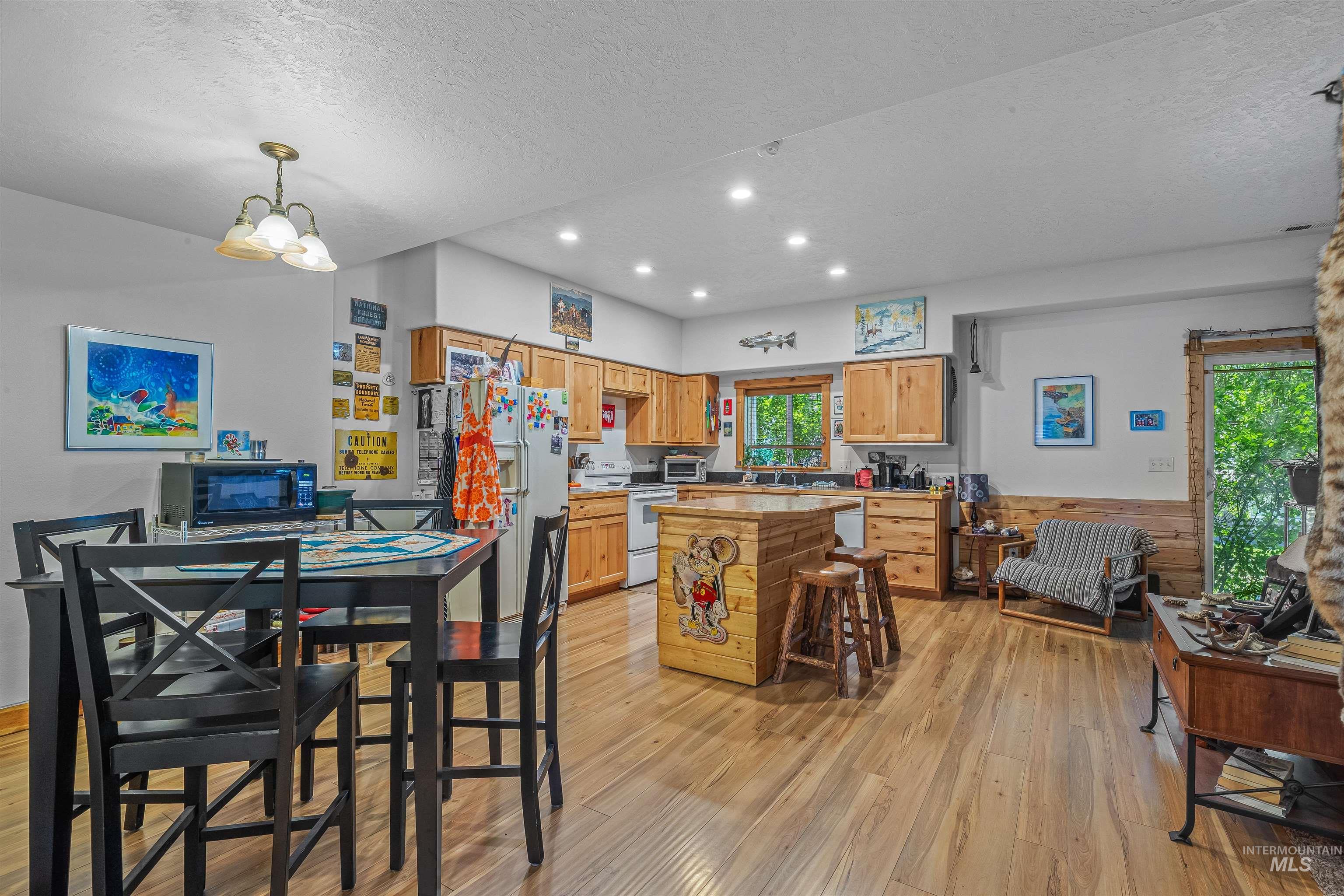 Kitchen featuring white appliances, light wood finished floors, a textured ceiling, light countertops, and recessed lighting