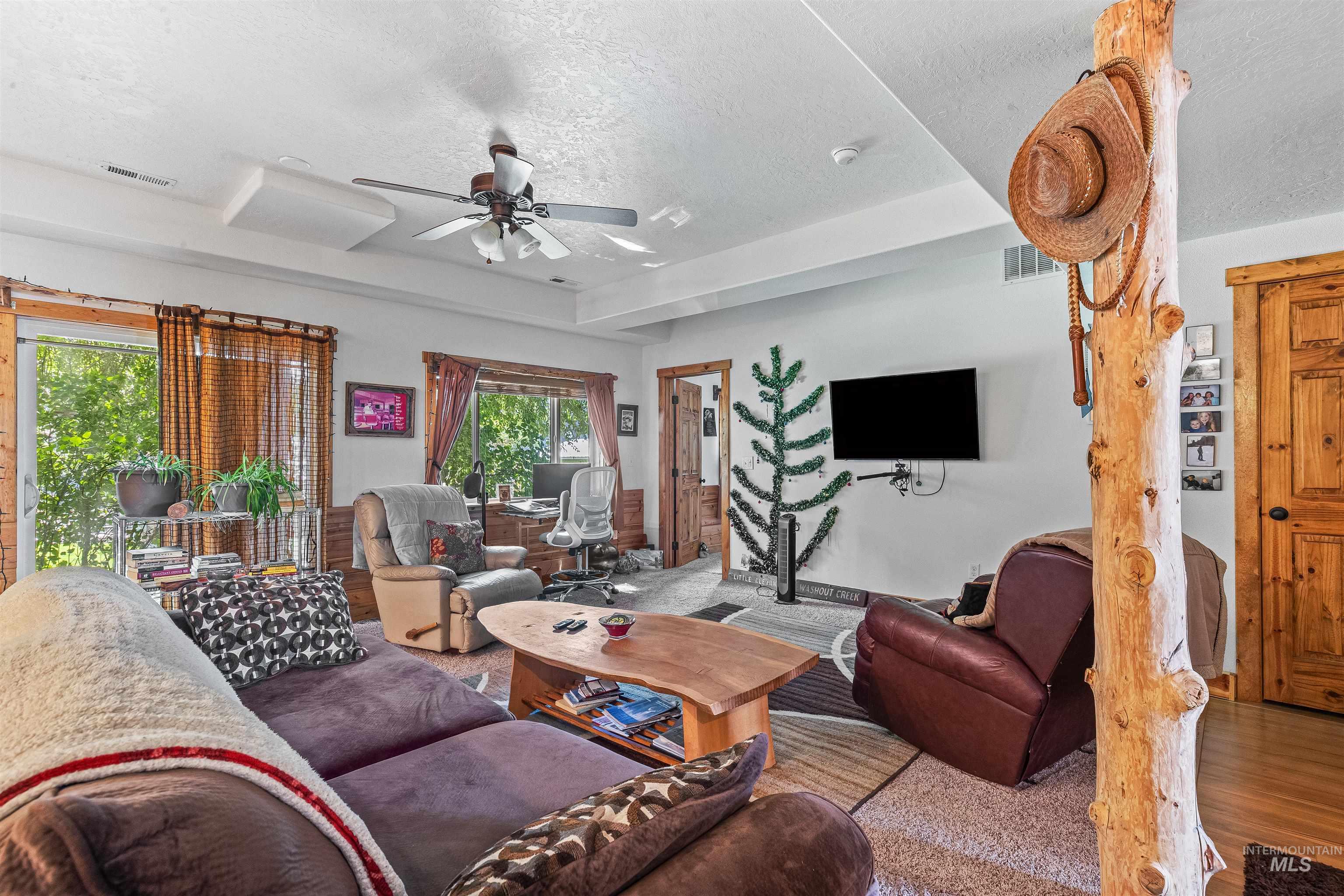 Living room featuring a textured ceiling, ceiling fan, and wood finished floors