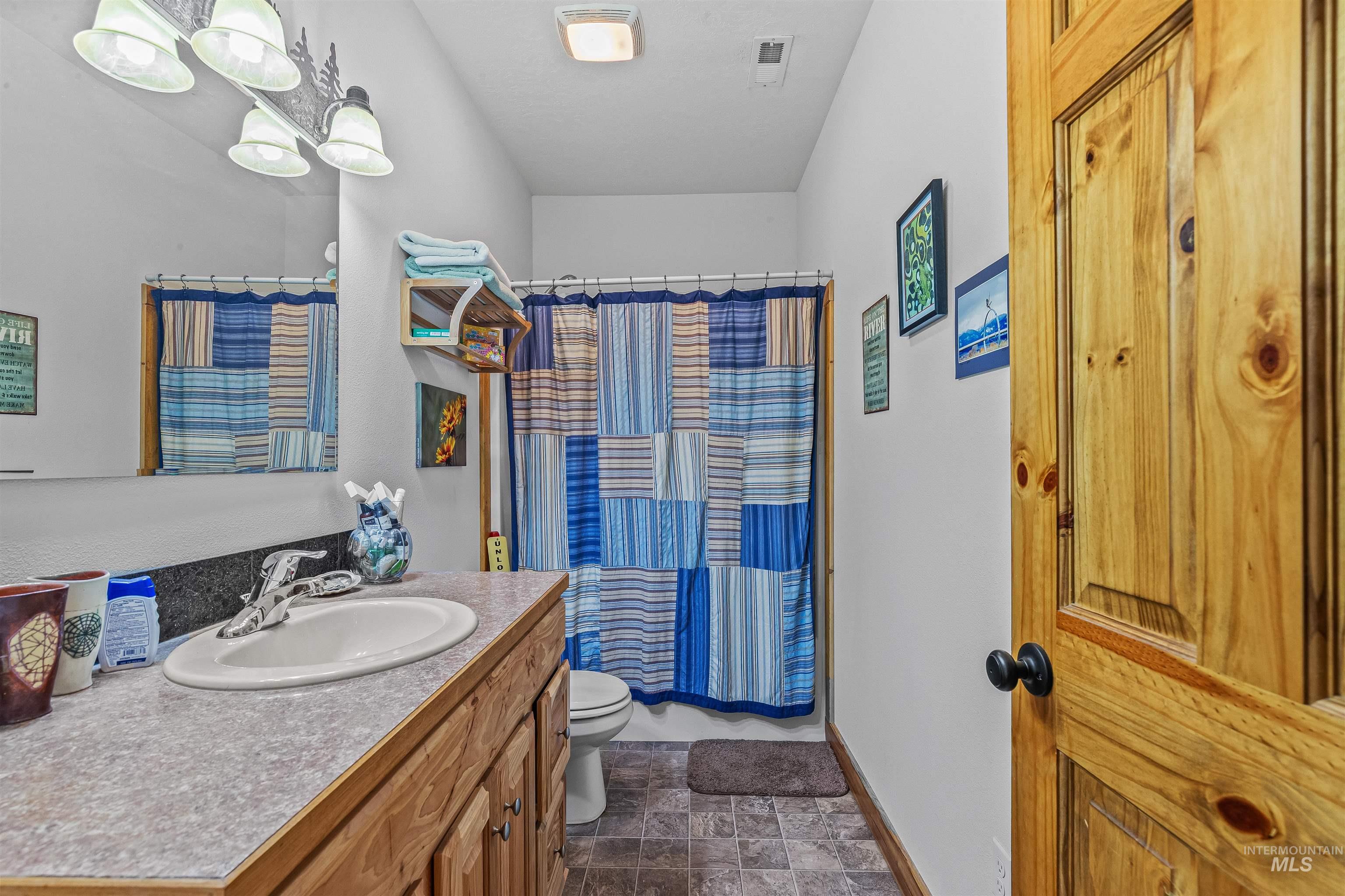 Full bathroom with vanity, curtained shower, and stone finish flooring