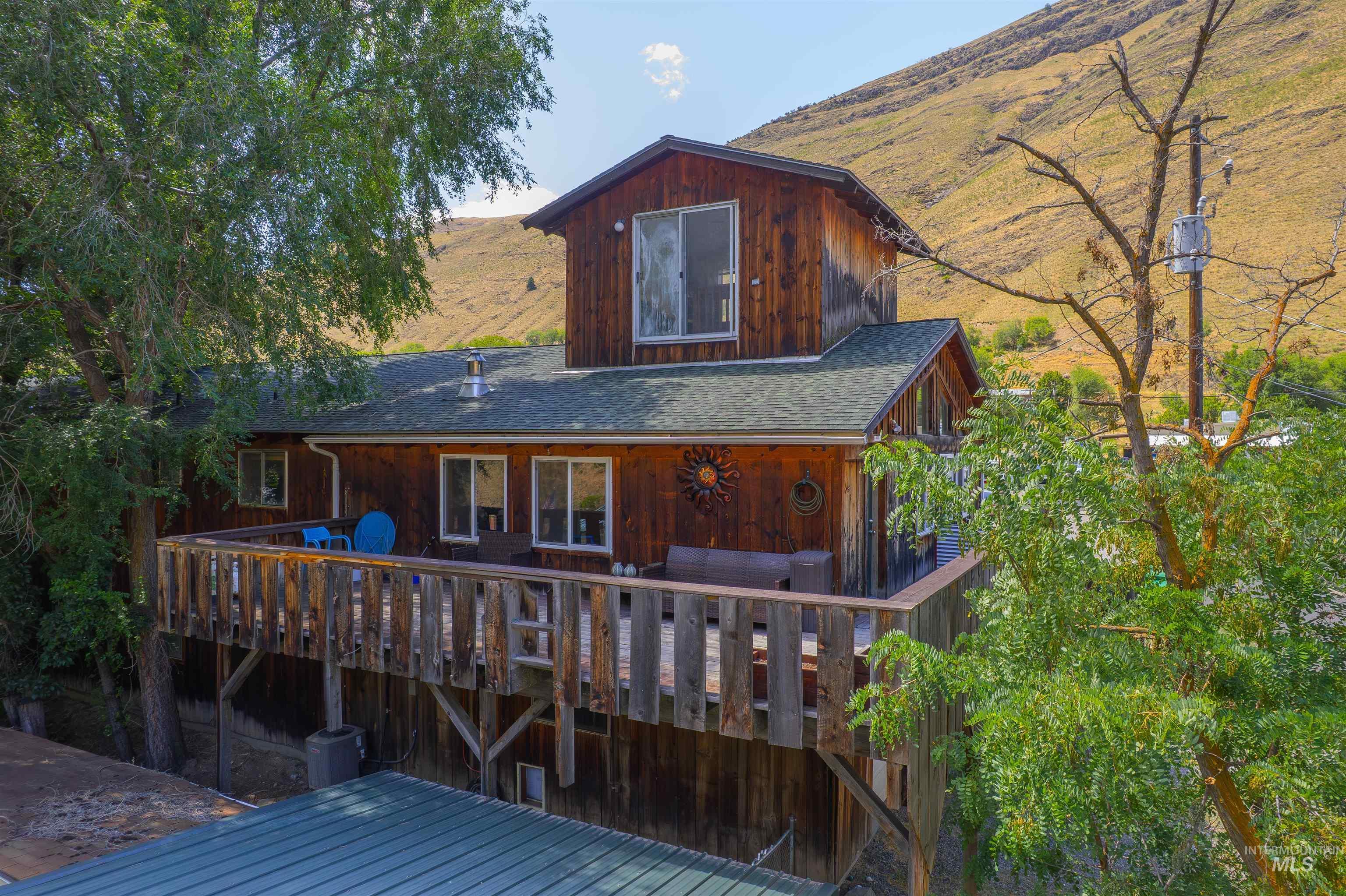 Rear view of house featuring a deck with mountain view and a shingled roof
