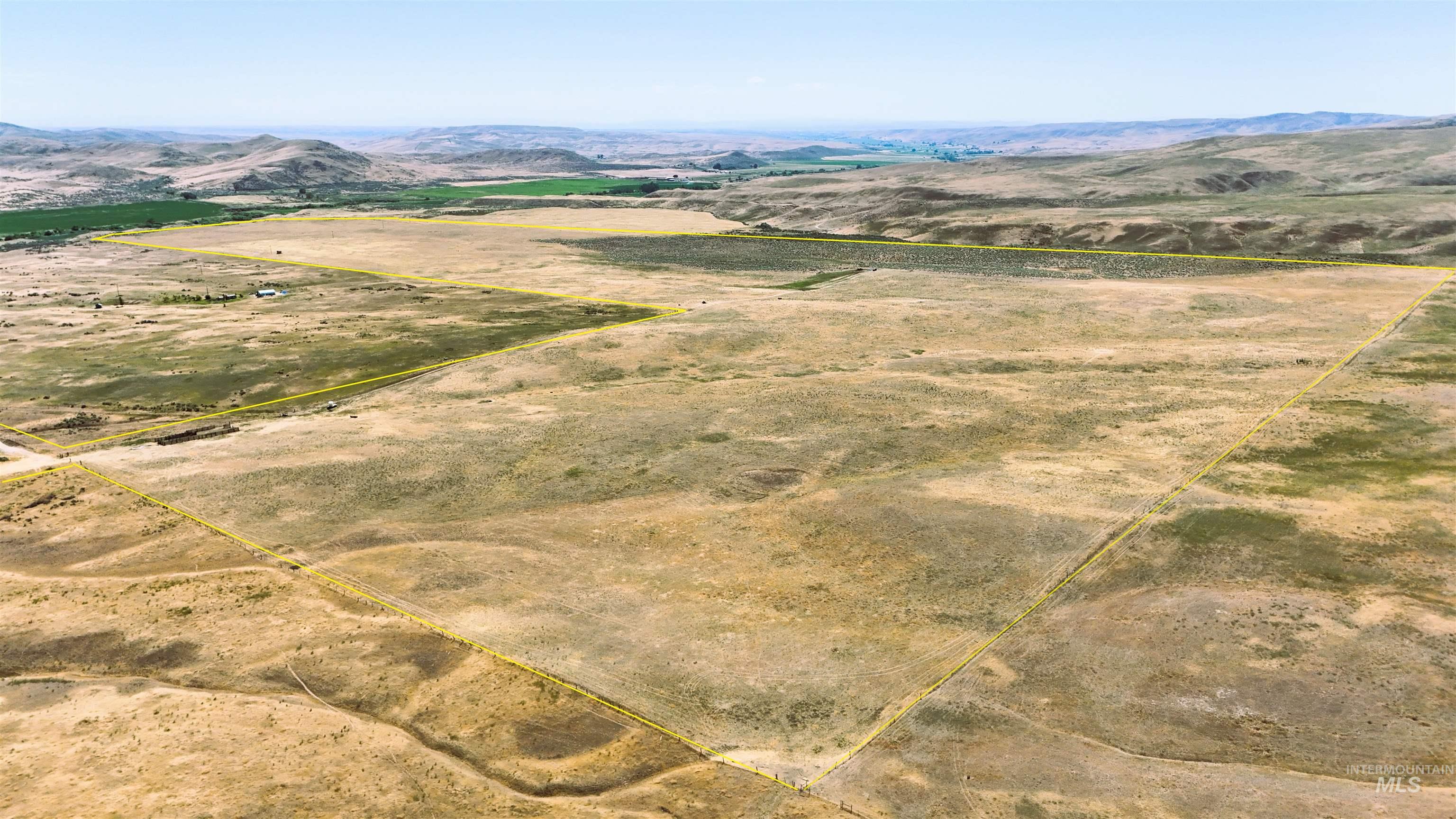 Aerial view of sparsely populated area with property parcel outlined and a mountainous background