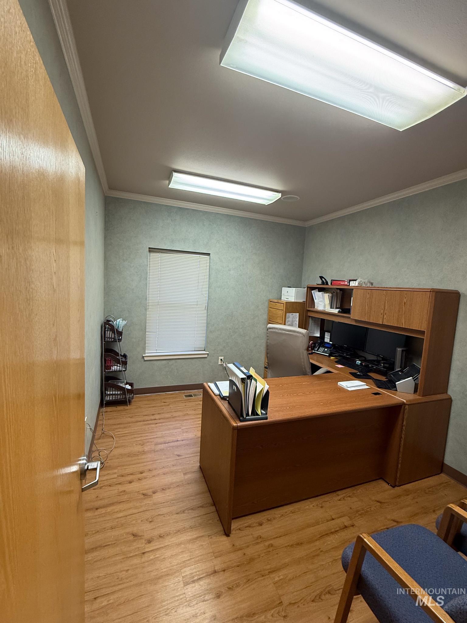 Office space featuring light wood-style flooring and crown molding