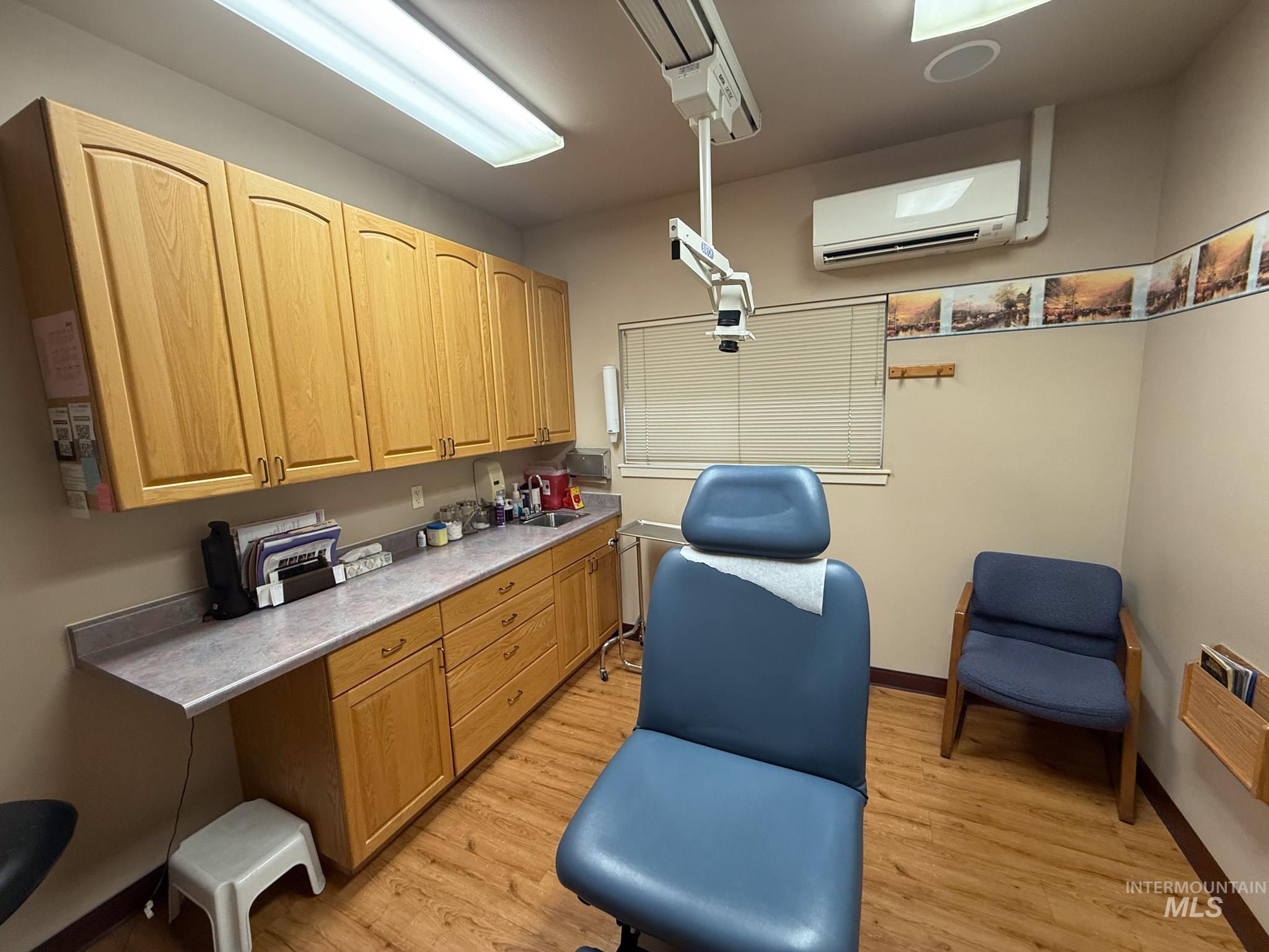 Kitchen with a wall mounted air conditioner, light wood finished floors, light countertops, and light brown cabinets