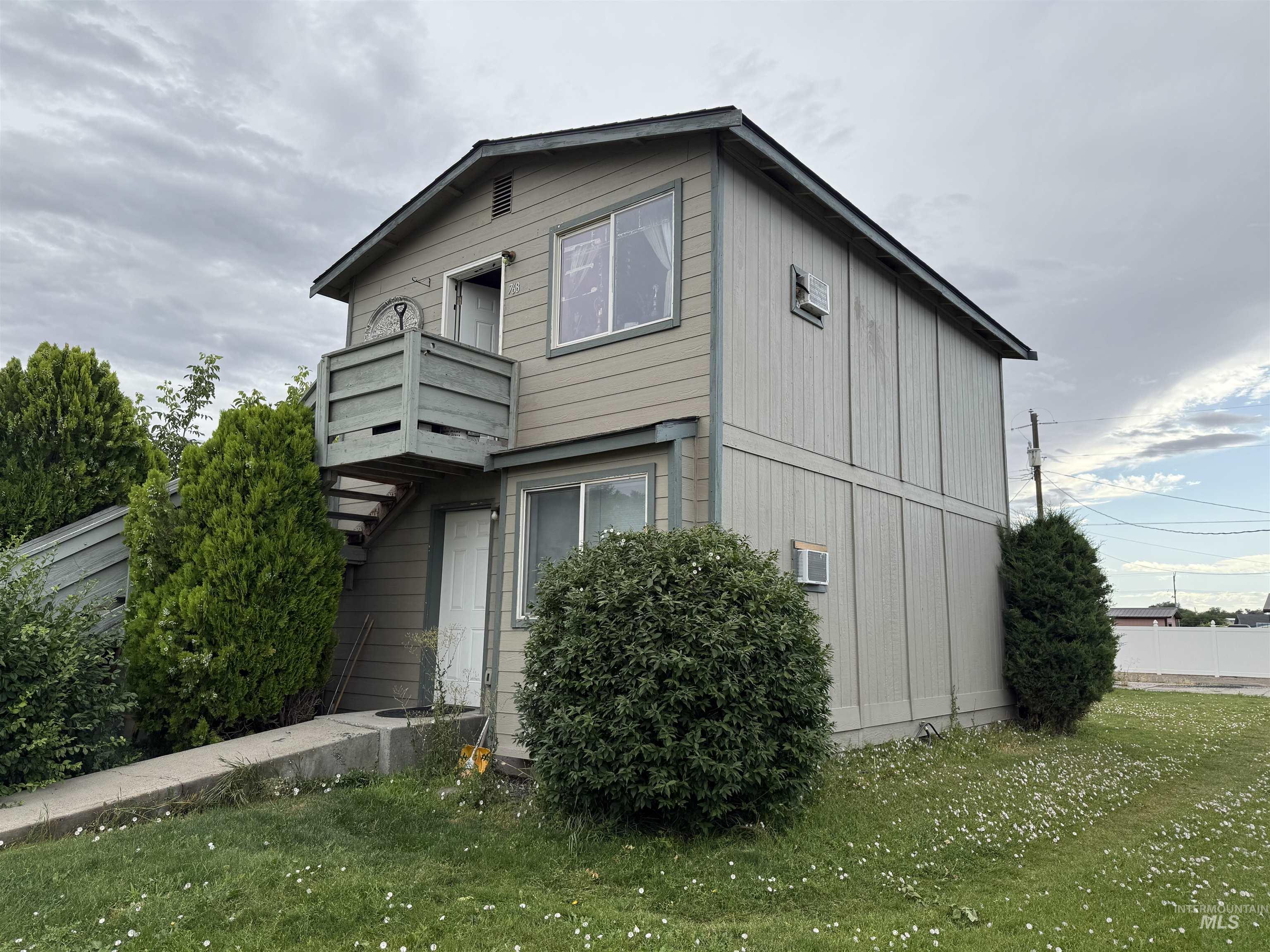 View of side of property with a balcony, a yard, and a wall mounted AC