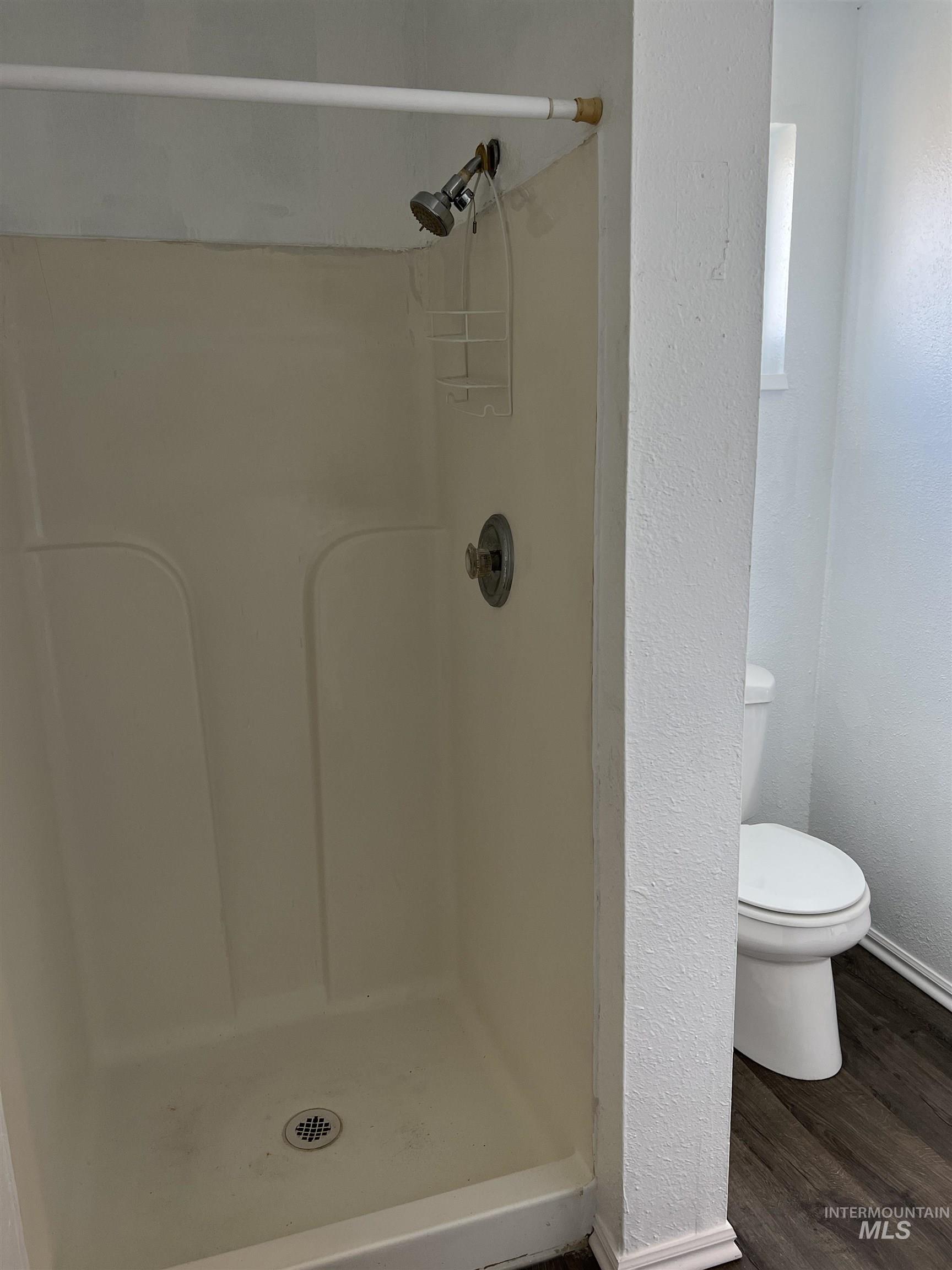 Full bathroom featuring a stall shower and wood finished floors