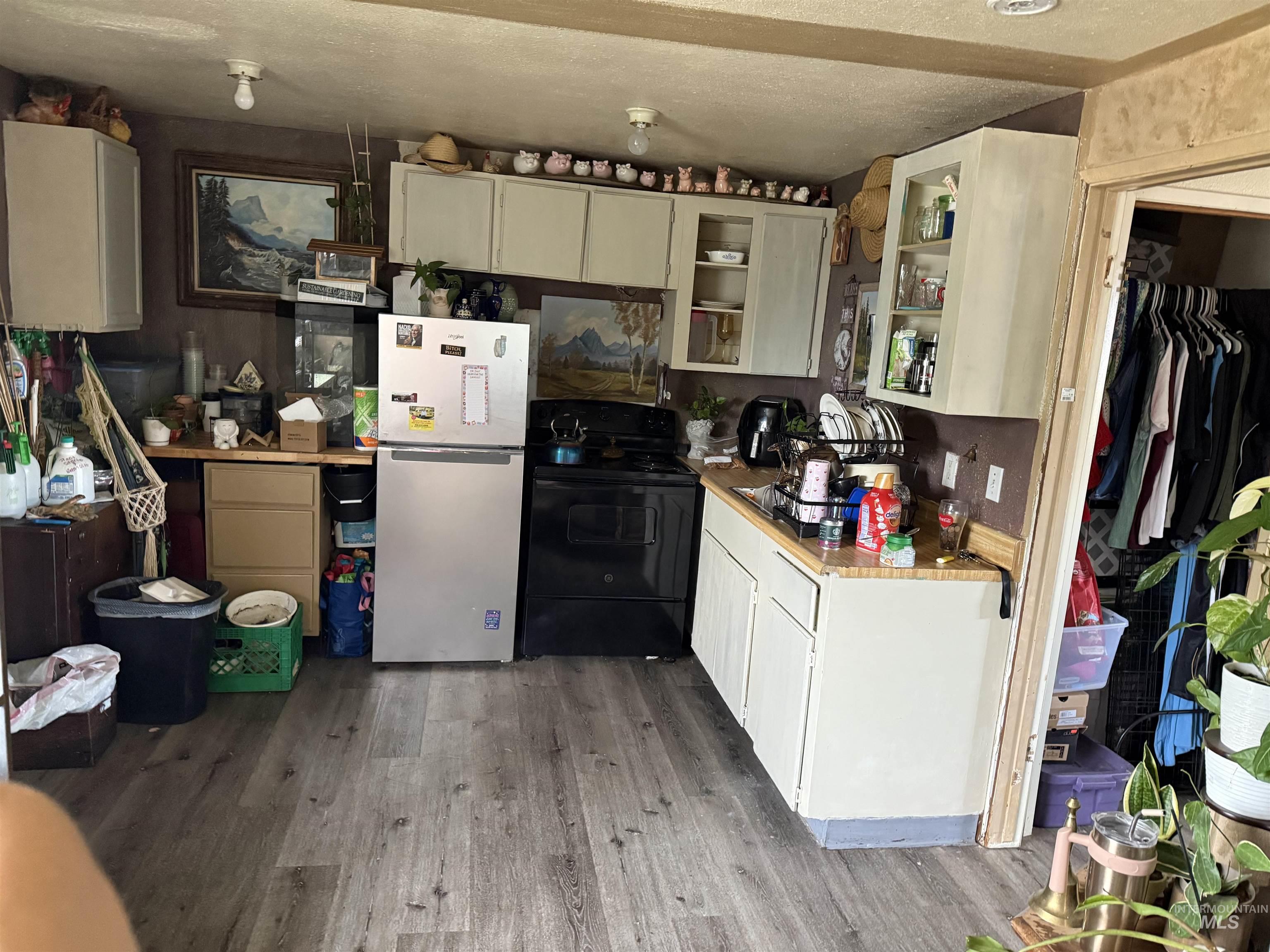 Kitchen featuring freestanding refrigerator, black range with electric cooktop, light wood-style flooring, light countertops, and glass insert cabinets