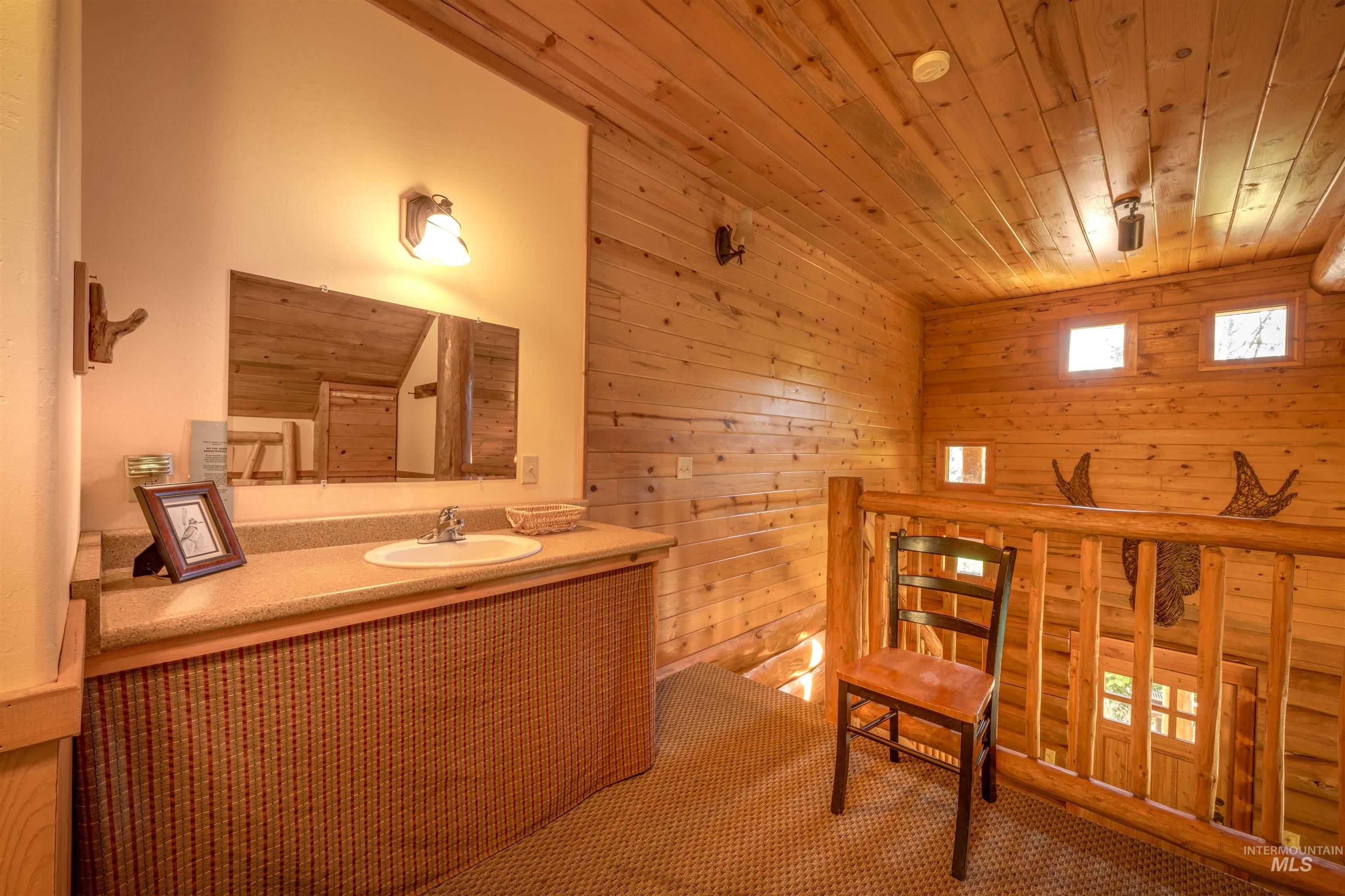 Bathroom with wood walls, wood ceiling, and vanity